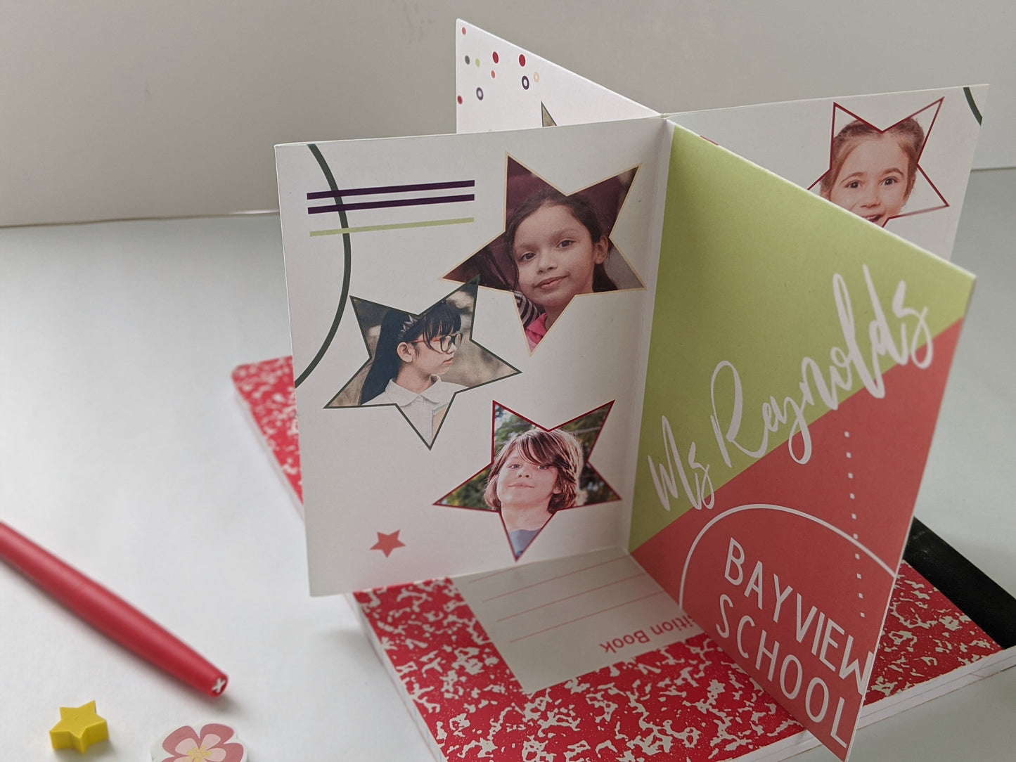 Centerpiece sitting on a red composition notebook with a felt tip pen and small erasers. The panels show photos of children inside colorful stars, a teacher and school name graphically arranged as a personal keepsake thank you.