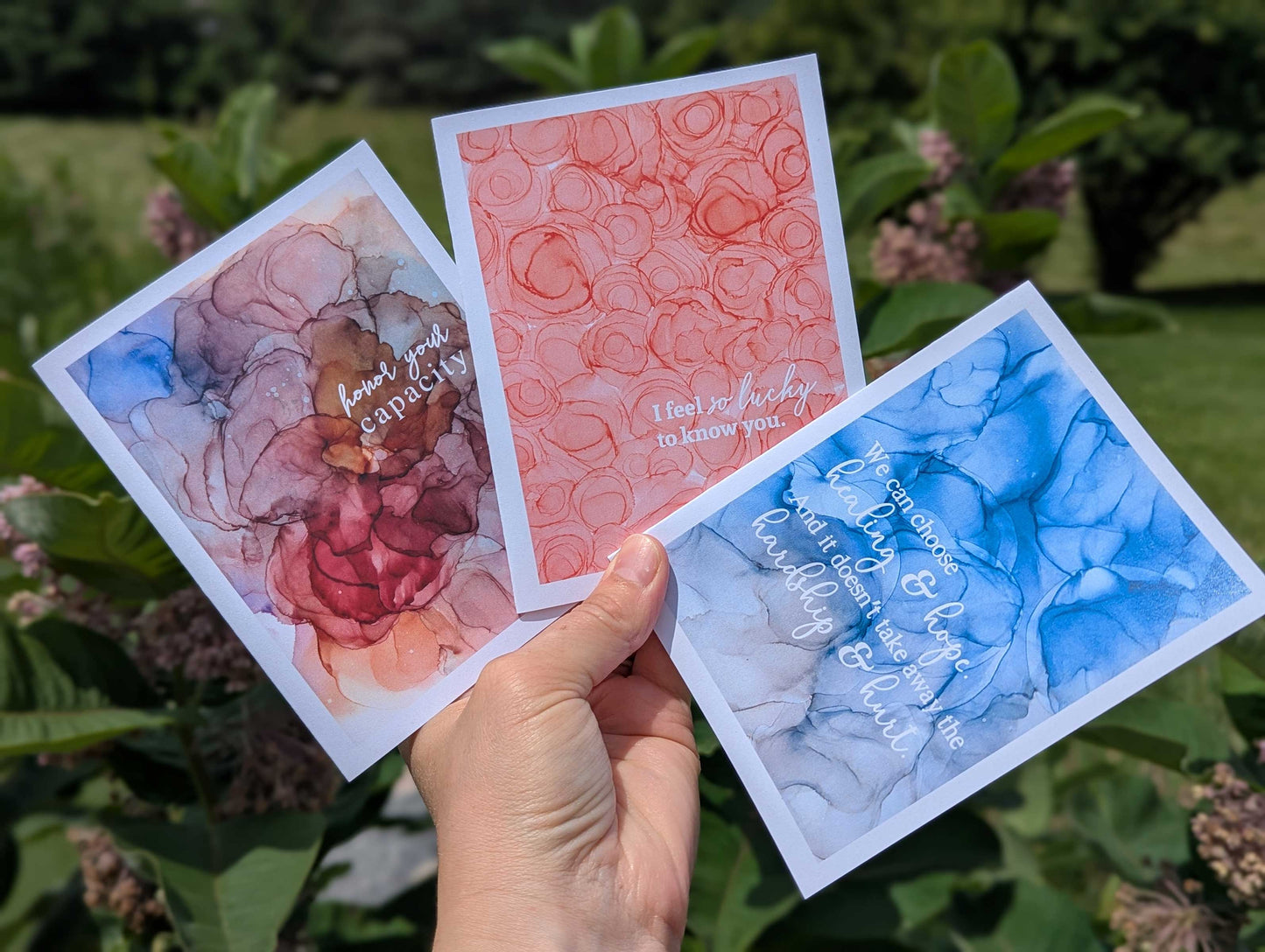Three empathy and friendship-themed greeting cards held by a hand with a natural background.