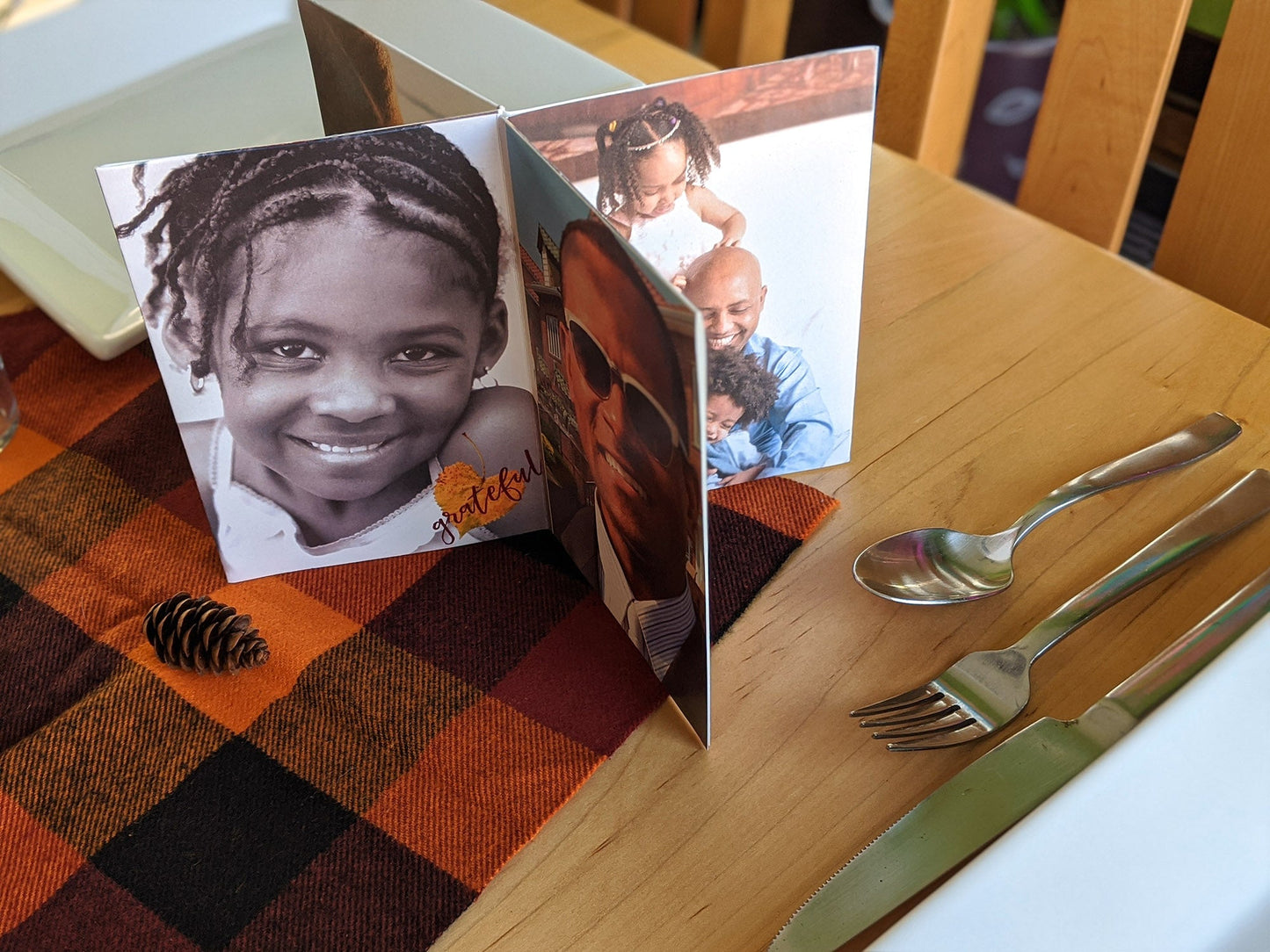 Centerpiece sitting on a wooden table among dishes, utensils and a checkered napkin in fall colors. The photos show a parent with two childen, a young professional in sunglasses, and a young child with braids smiling at the camera. There is an overlay of a heart shaped leaf and the word grateful.