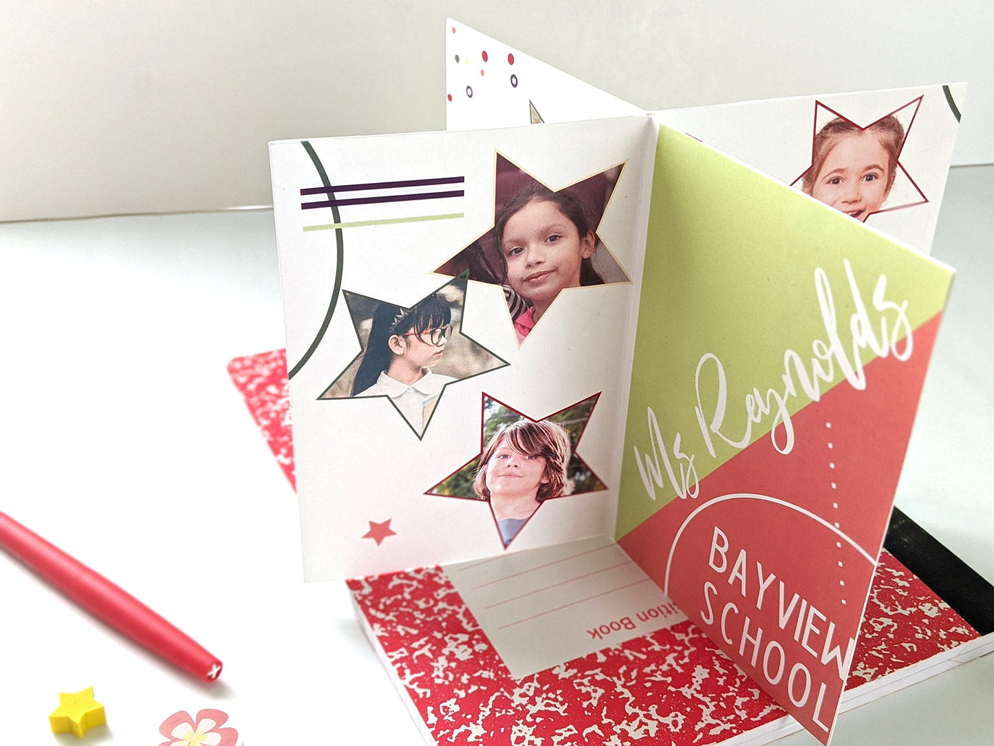Centerpiece sitting on a red composition notebook with a felt tip pen and small erasers. The panels show photos of children inside colorful stars, a teacher and school name graphically arranged as a personal keepsake thank you.