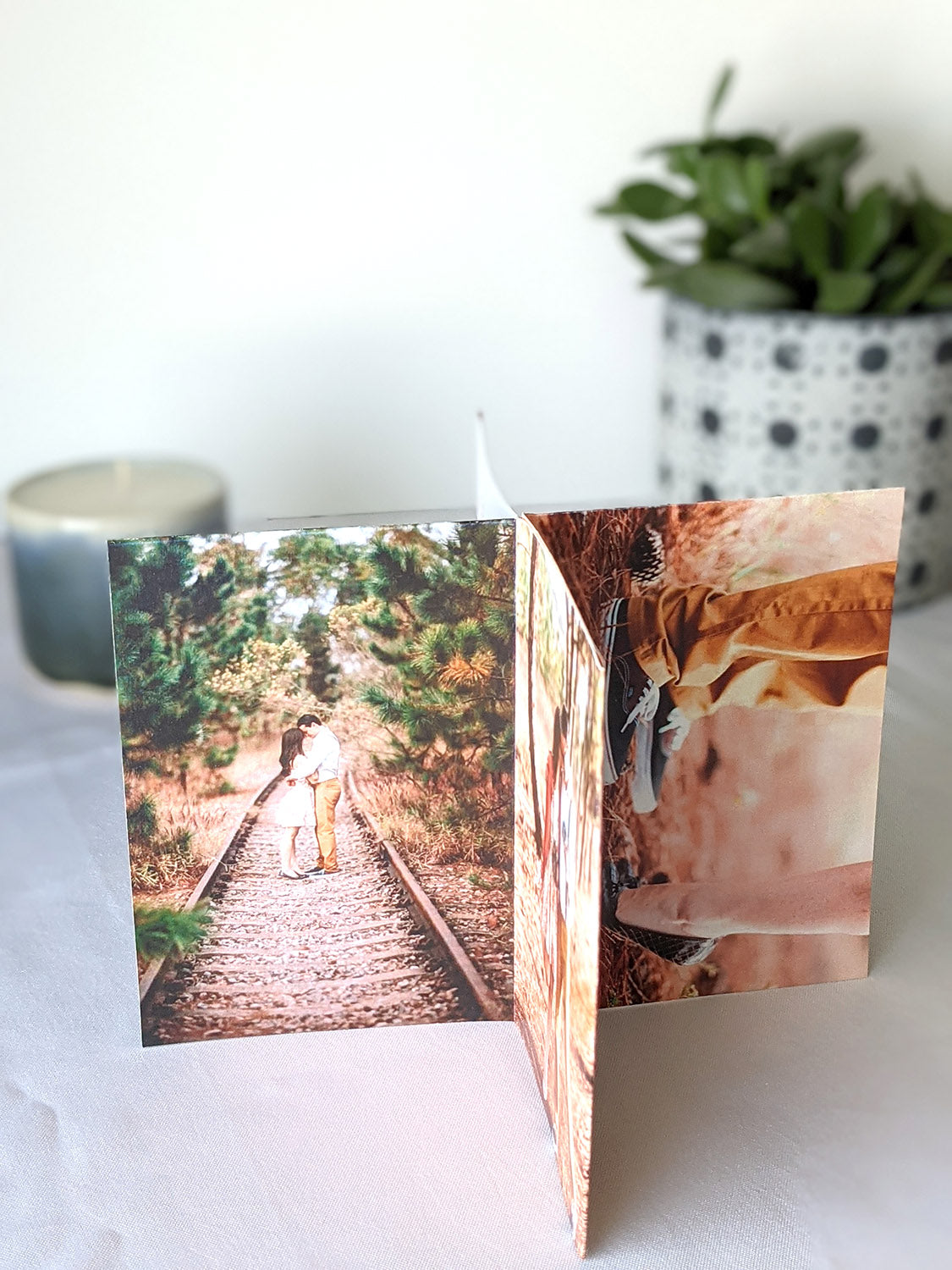 Centerpiece sitting on a white background with panels showing engagement photos of a couple standing in abandoned railroad tracks and one zoomed in detail of one standing on tip toes and the other shoes standing flat.