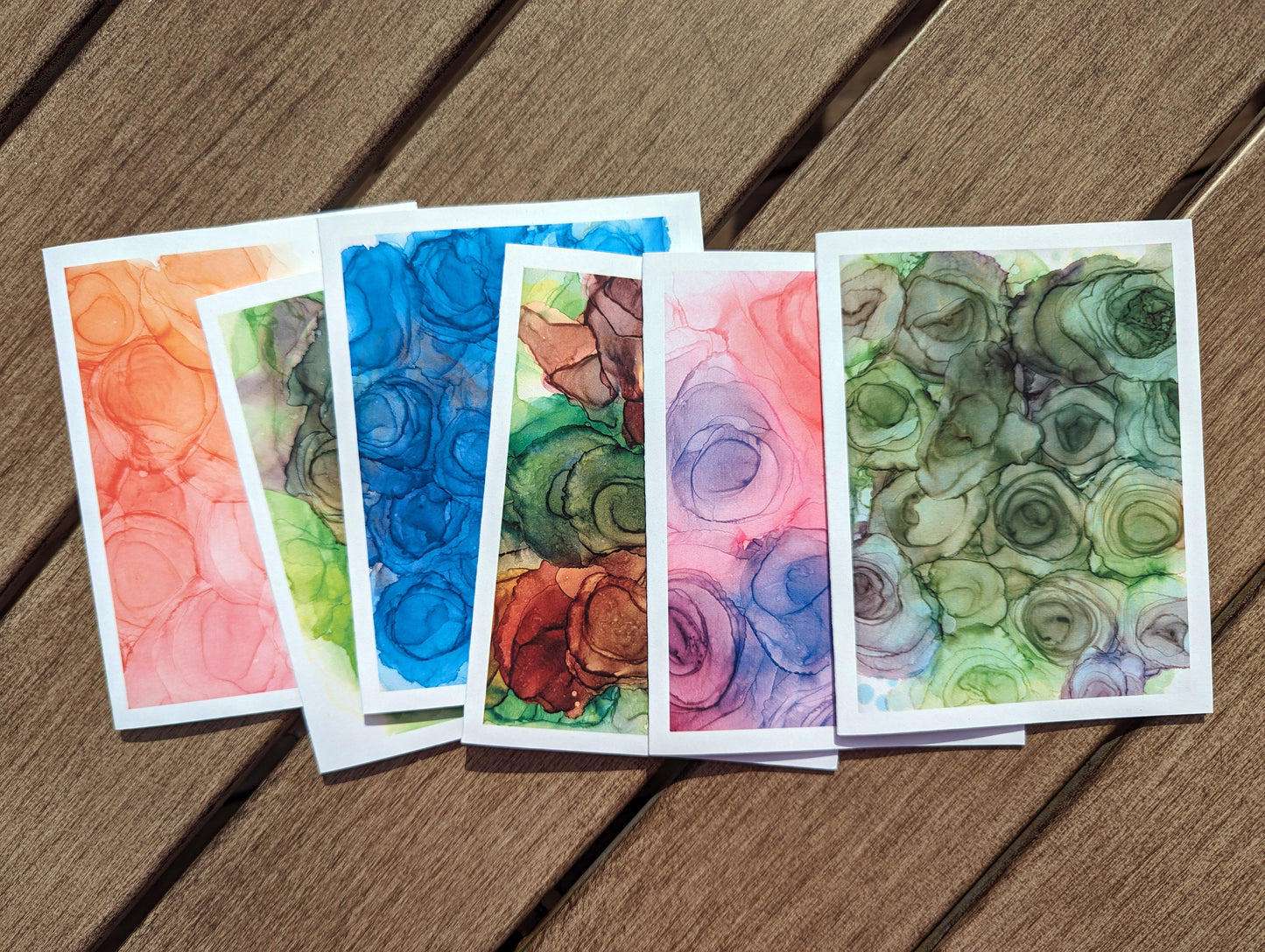 All 6 greeting cards laying on dark wooden boards.
