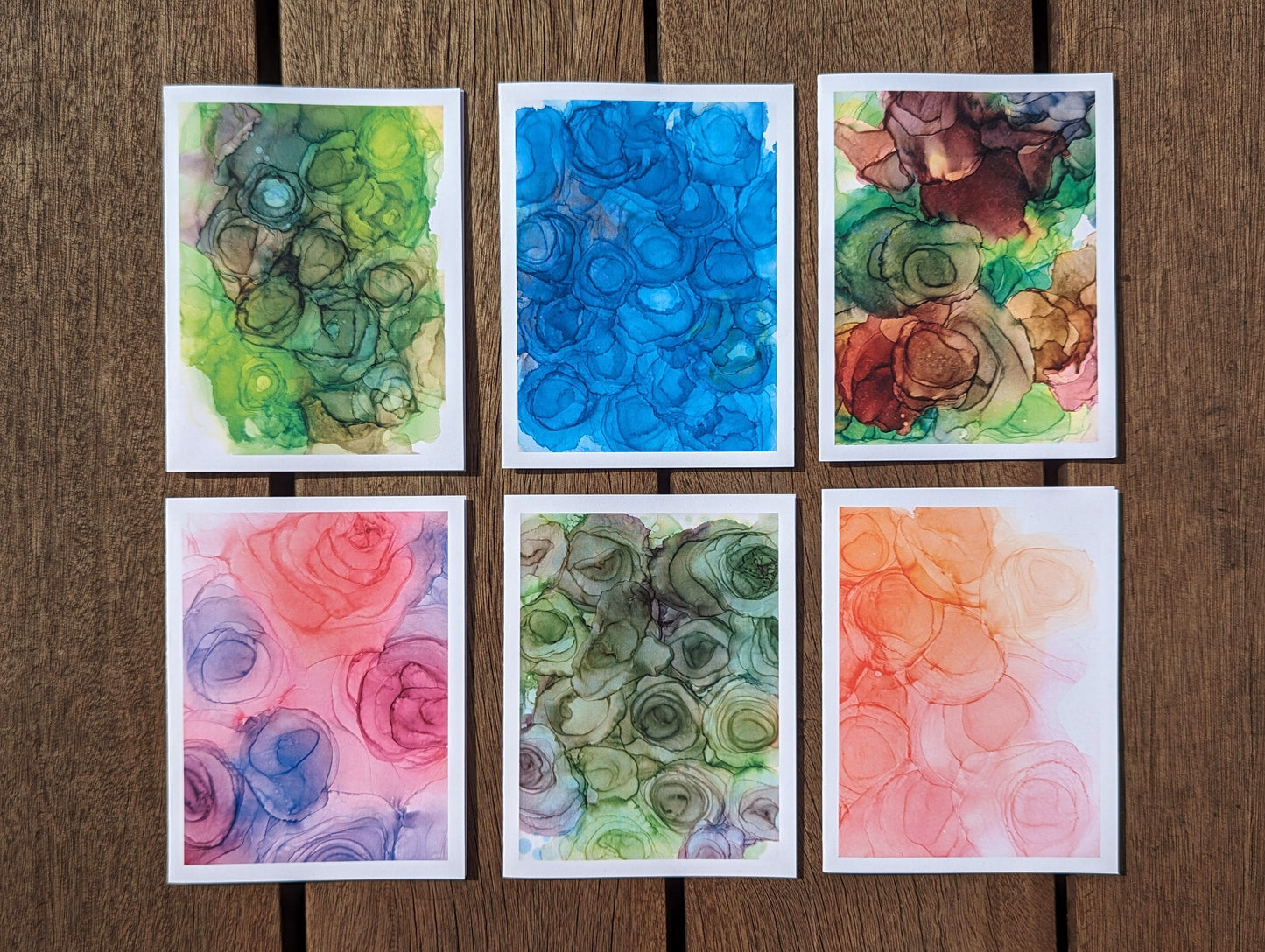All 6 greeting cards laying on dark wooden boards.