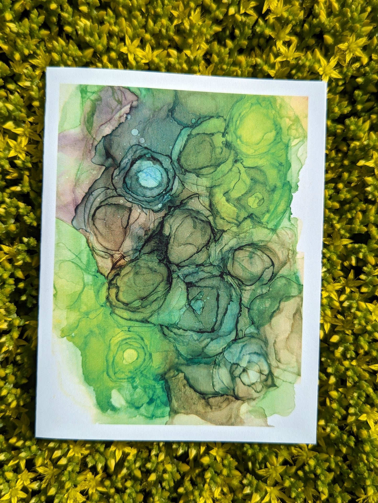 Hand holding a greeting card with tiny yellow flowers in the background.