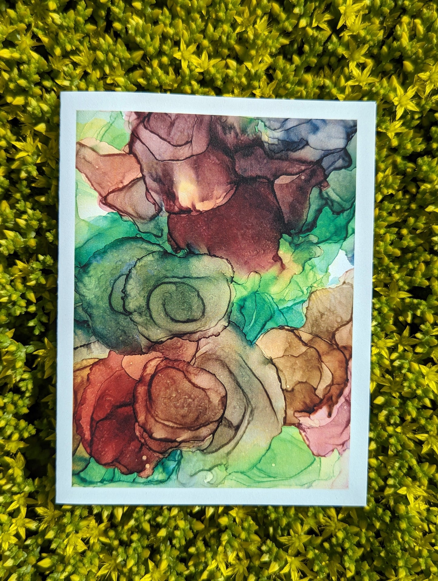 Hand holding a greeting card with green leaves in the background.