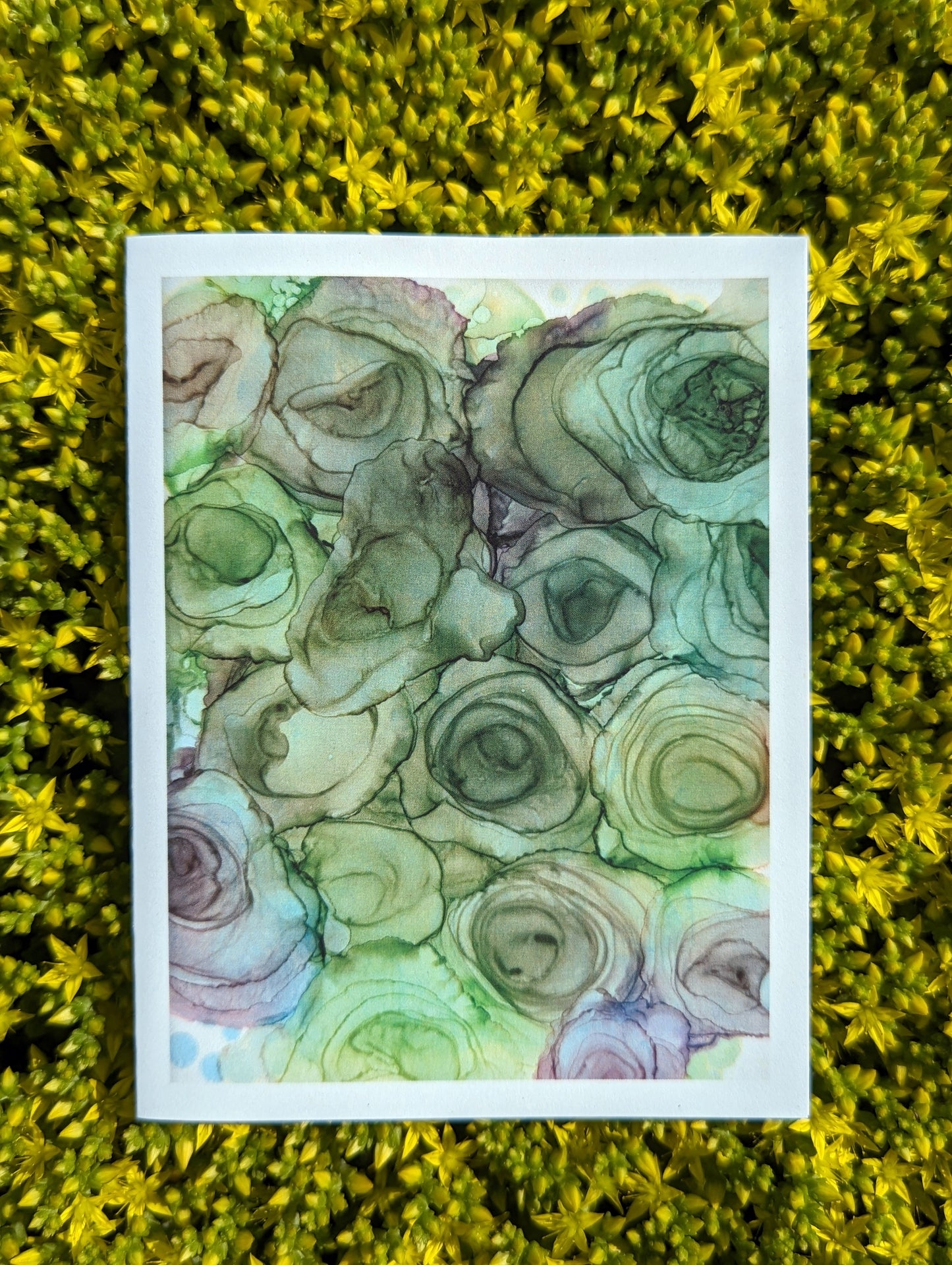 Hand holding a greeting card with tiny yellow flowers in the background.