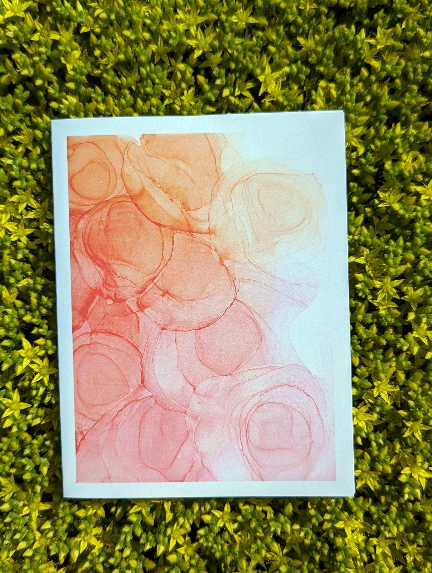 Hand holding a greeting card with tiny yellow flowers in the background.