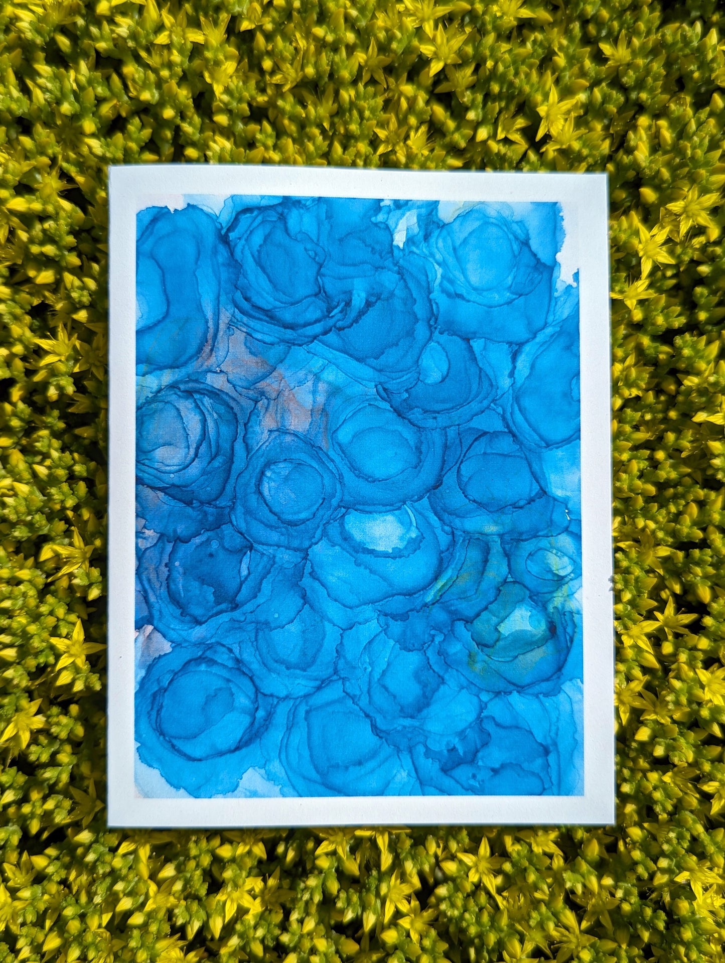 Hand holding a greeting card with tiny yellow flowers in the background.