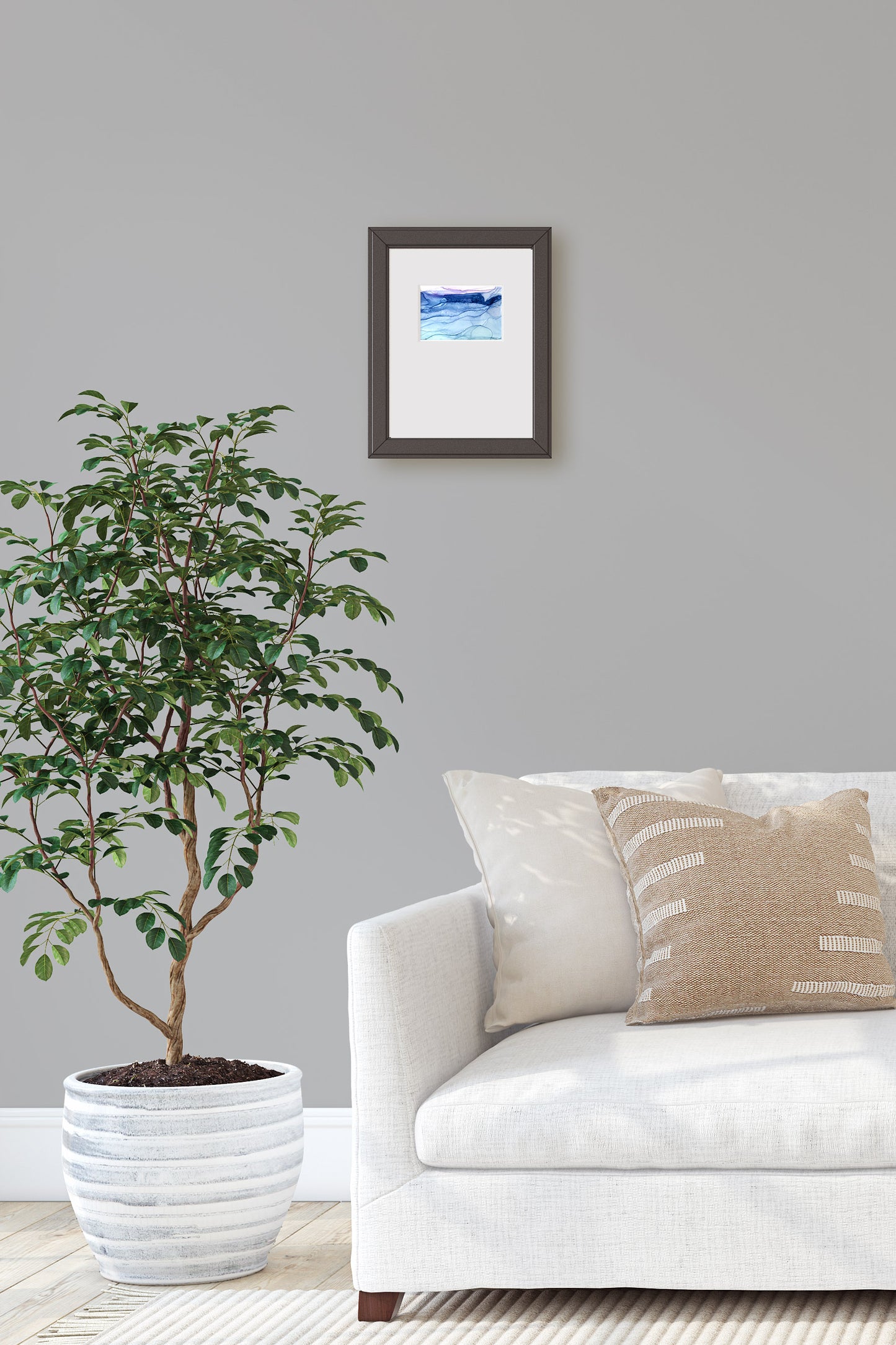 Digital mockup of the painting framed in black hung above a sofa on a light grey wall. A potted tree sits on a light wood floor off to the side.