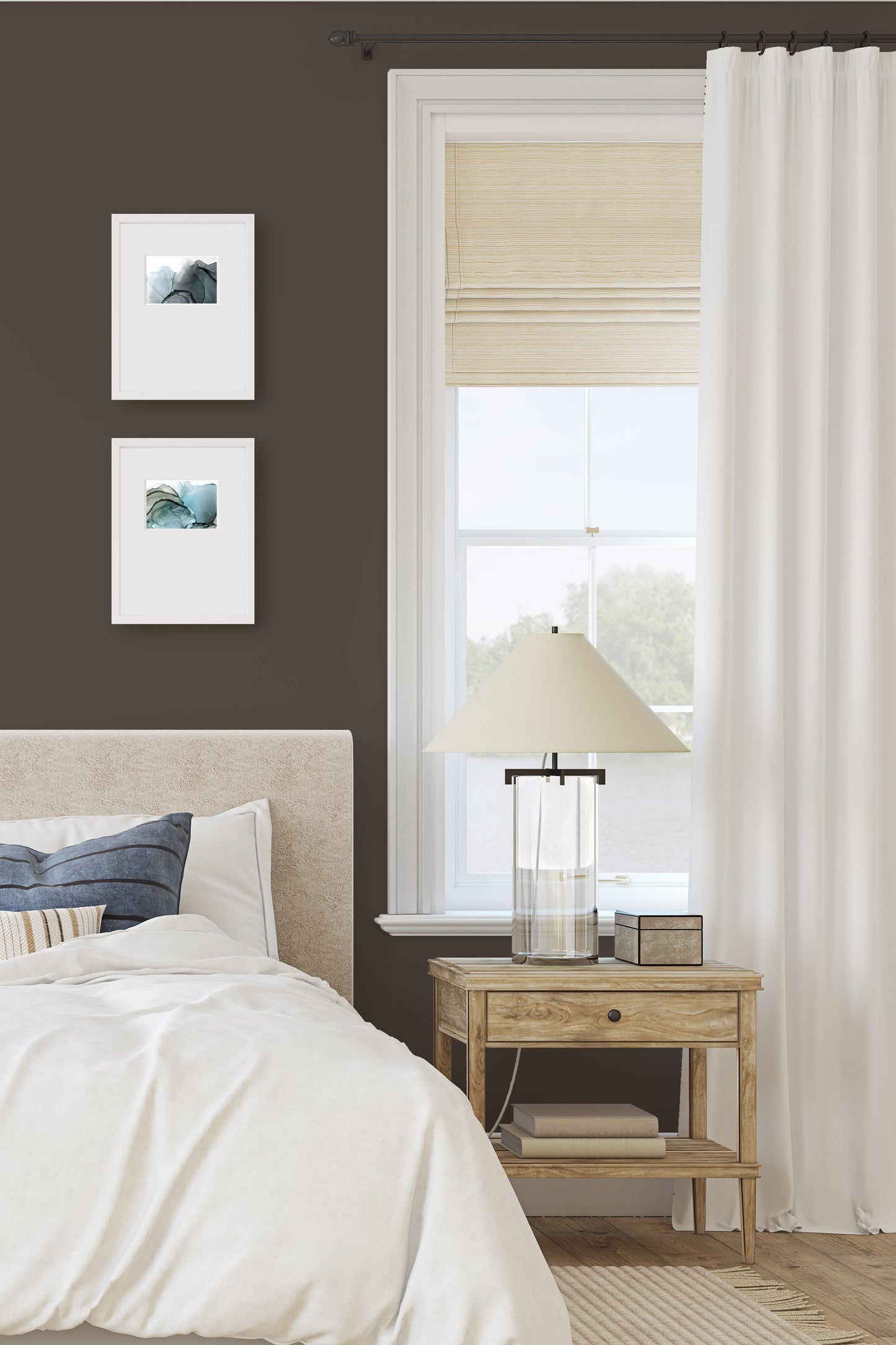 Digital mockup of two paintings framed in white against a brown wall in a bedroom next to a window with a bed and an end table in the foreground.
