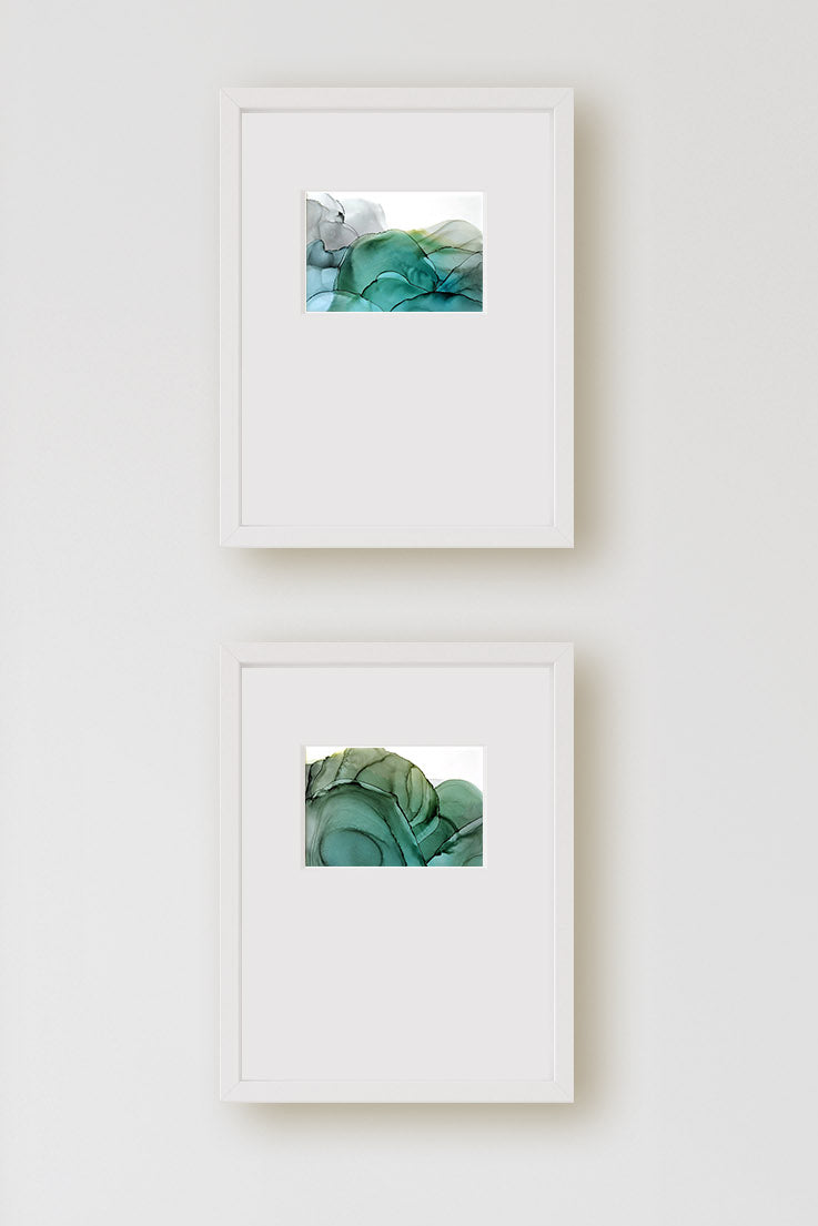 Zoomed in view of the two paintings hung on a light grey wall.