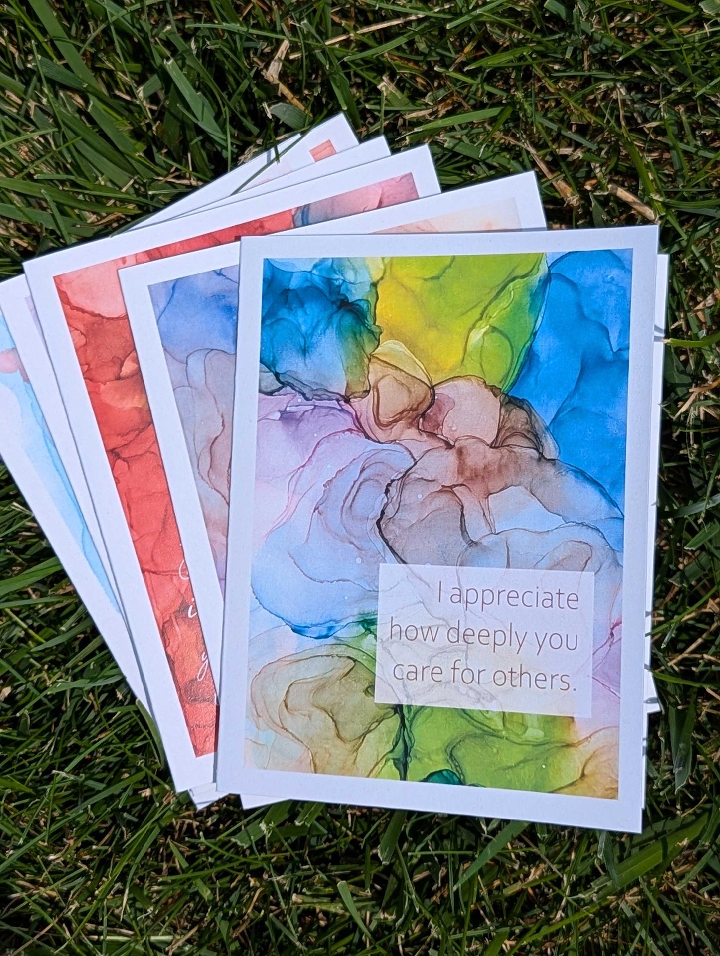 Stack of greeting cards with artistic designs on a grassy background