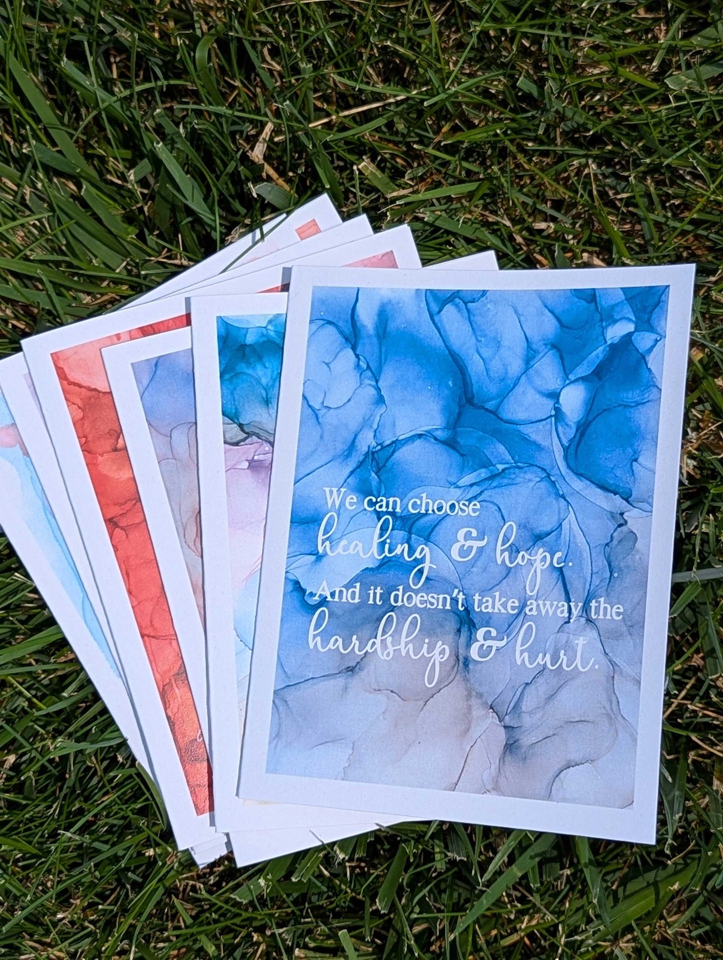 Stack of greeting cards with motivational text on a grass background