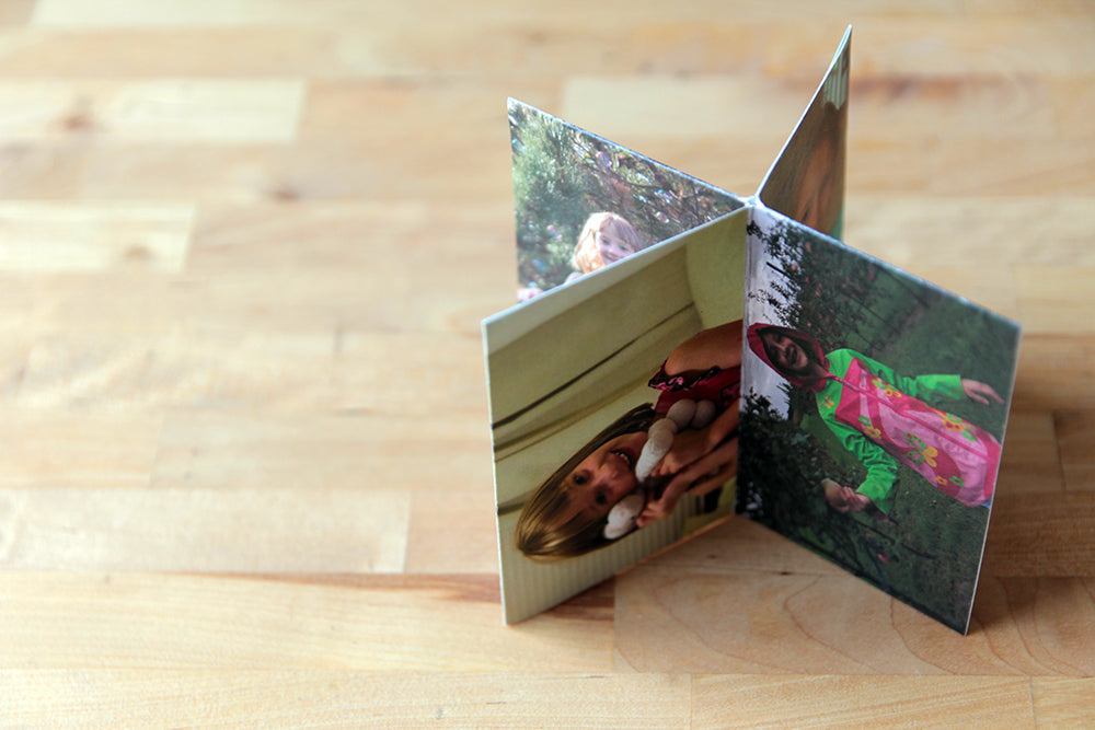 Centerpiece standing on a wooden table top with photos of a young child snuggling a stuffed animal and standing in an apple orchard in a brightly colored raincoat.