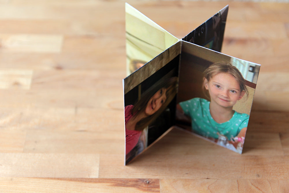Centerpiece standing on a wooden table top with panels showing a child smiling at the camera in different outfits.