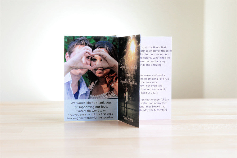 Centerpiece sitting on a wooden table with a neutral wall in the background. The panels show engagement photos of a couple forming a heart with their hands, a thank you messge, and their relationship story.