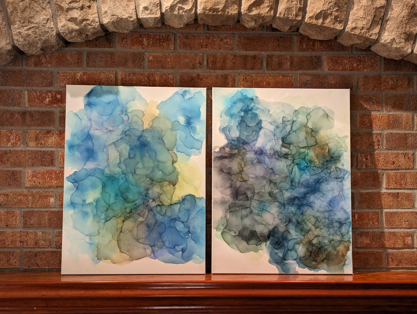 Two canvases shown side by side indoors on a fireplace mantel.