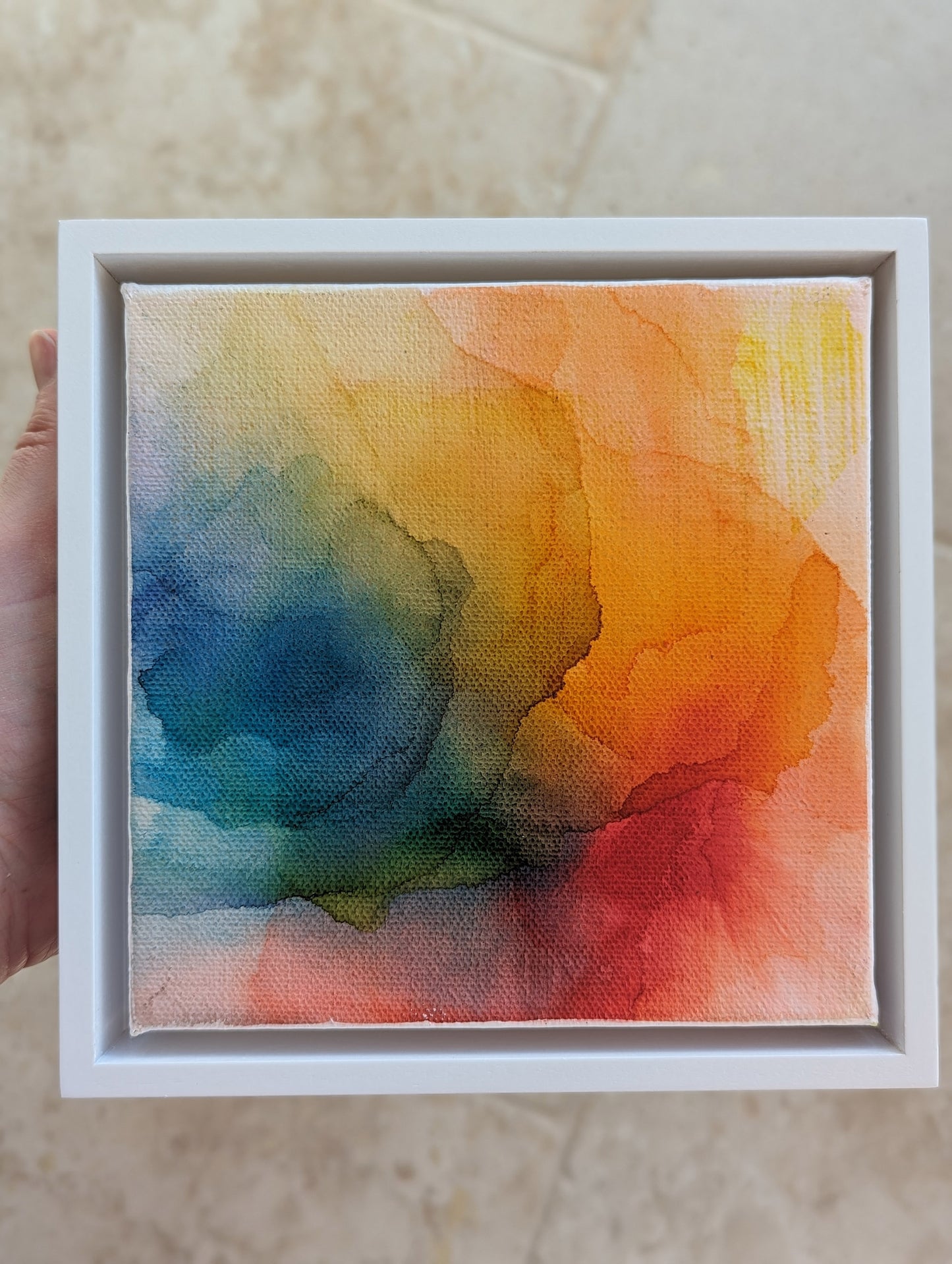 Hand holding the white float framed At the And the Promise of Sunshine indoors.