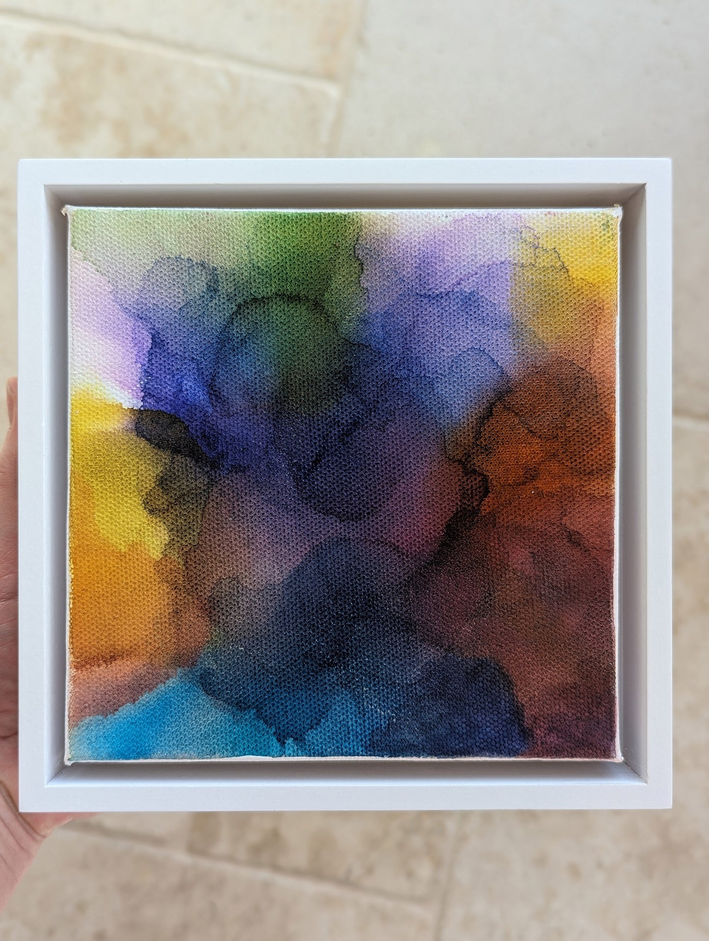 Hand holding the white float framed At the End of the Storm indoors.