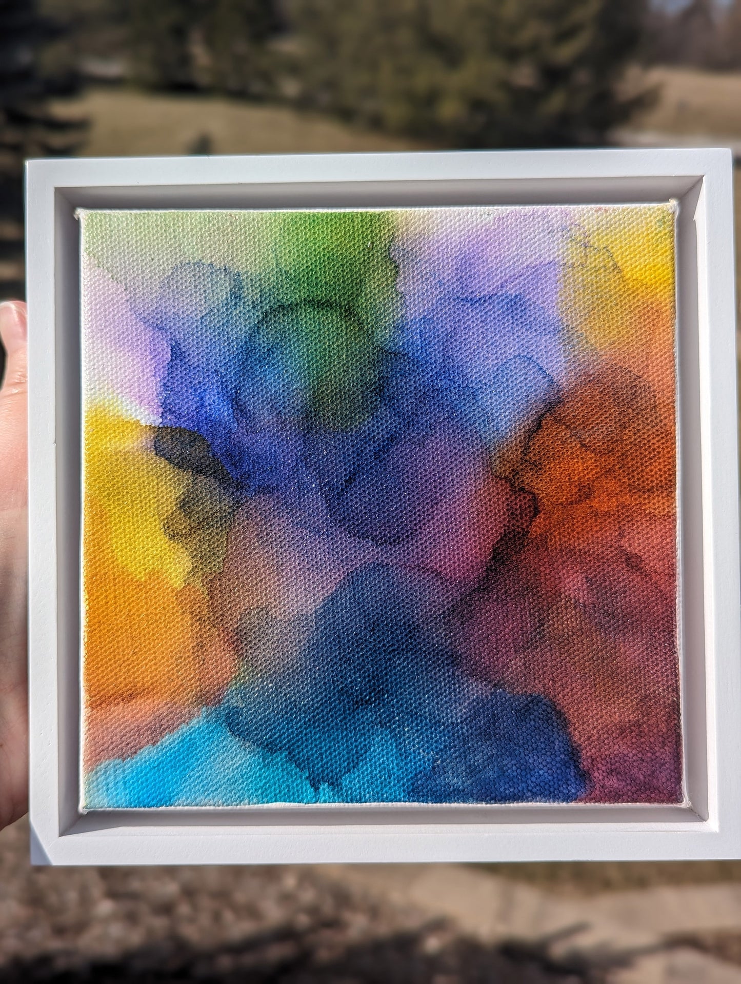 Hand holding the white float framed At the End of the Storm outdoors.