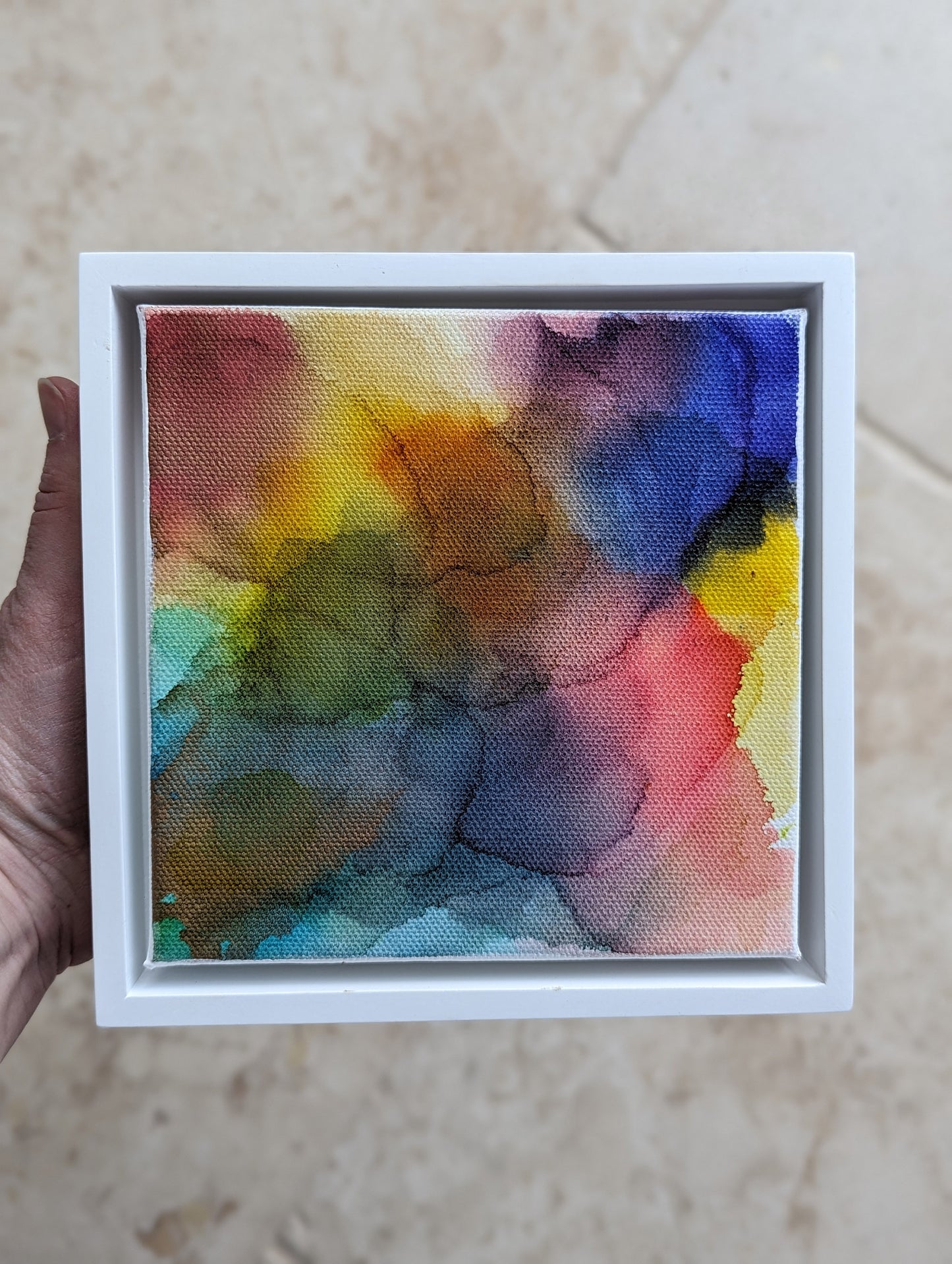 Hand holding the white float framed Bending and Bounding indoors.