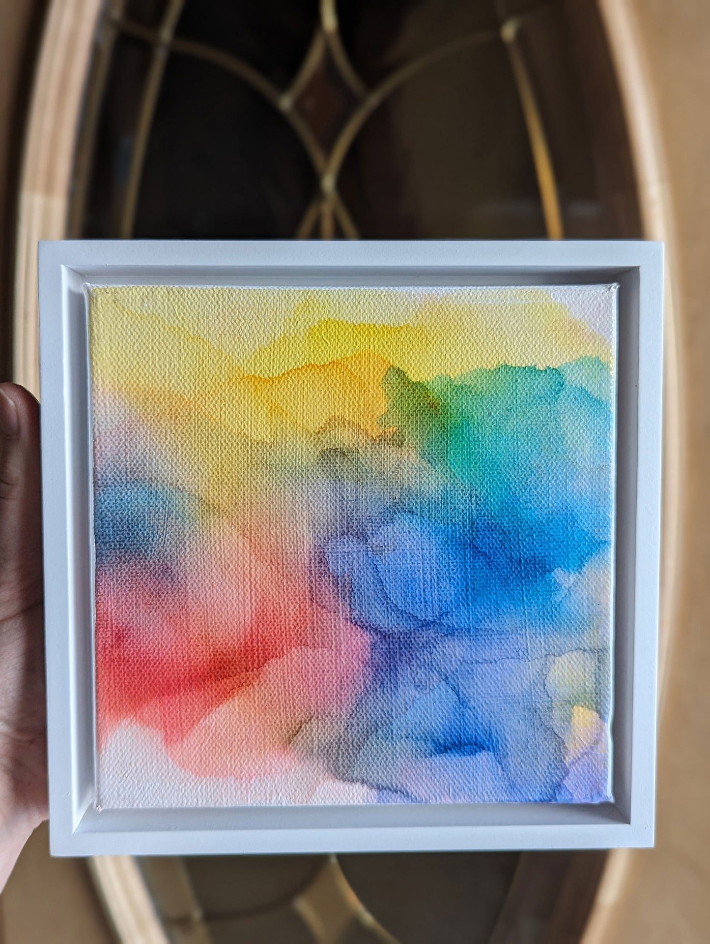 Hand holding the white float framed Possibilities of Hope with light coming in from a doorway.