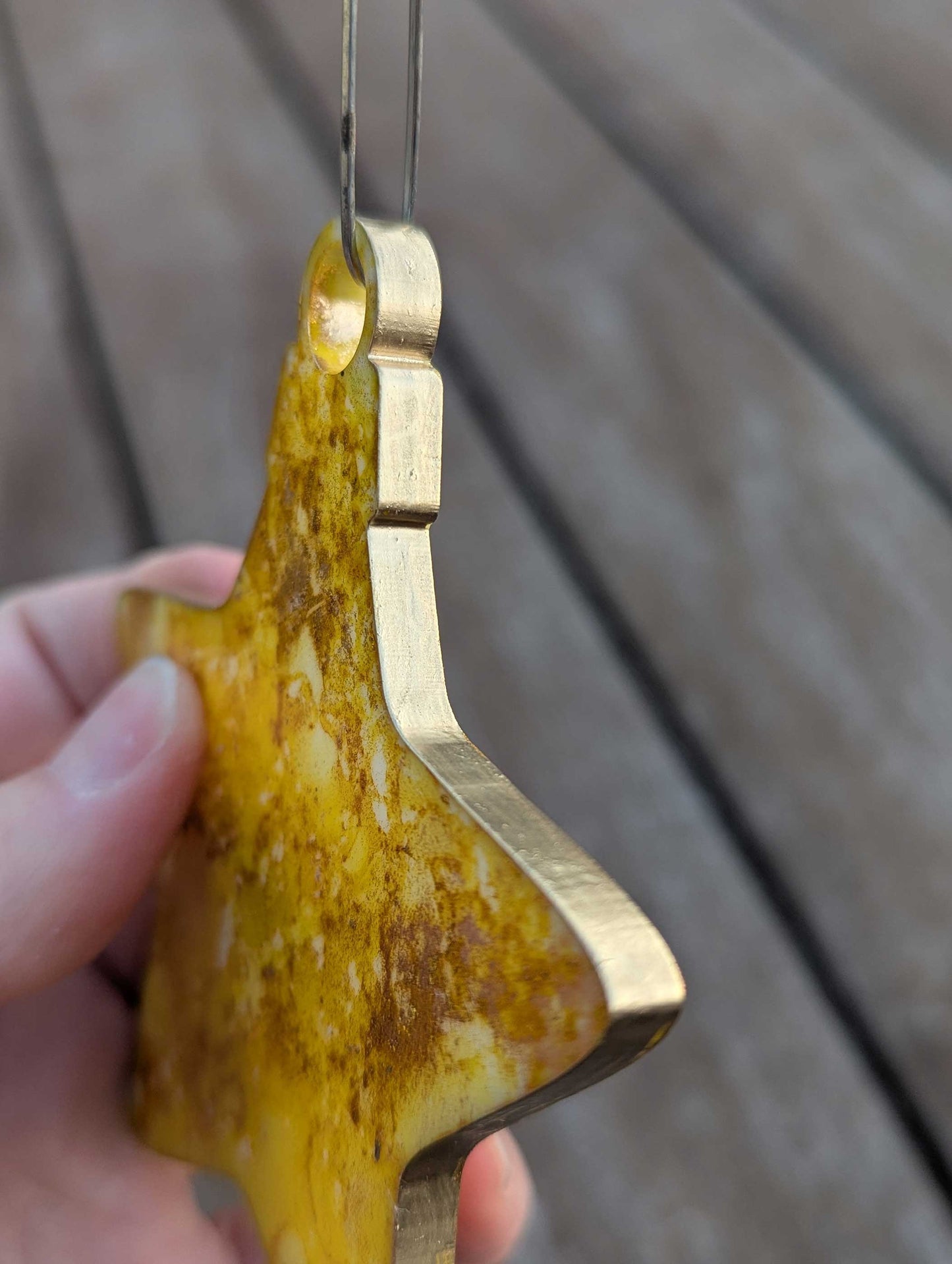 Hand holding a yellow star ornament with against a wooden background