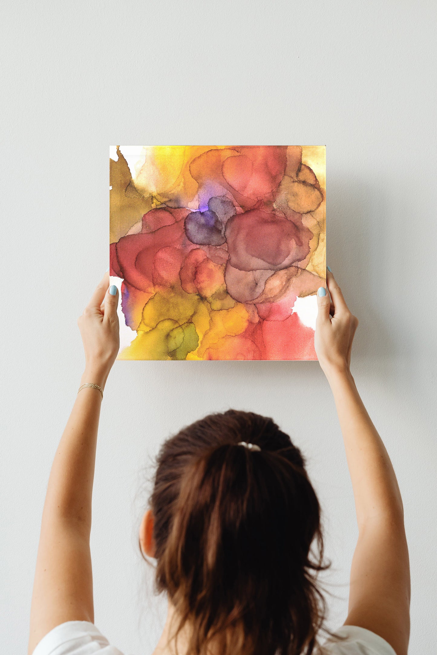 Digital mockup of a person's hands hold the canvas above their head against a wall.