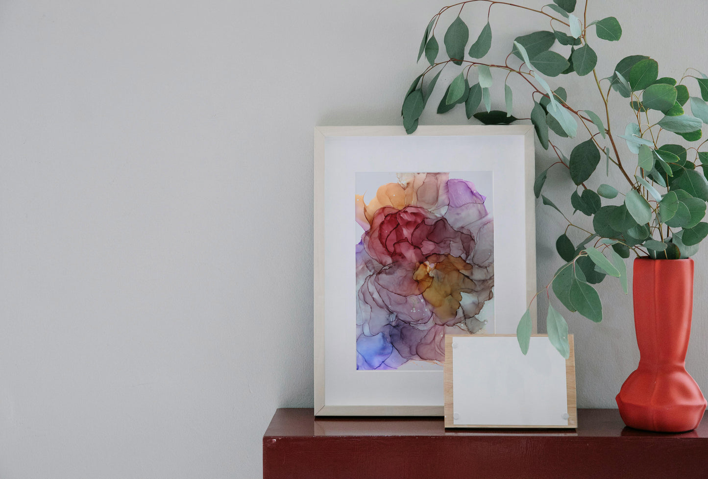 Digital mockup of Beautiful thoughts framed in light wood sitting on a wooden table against a white wall. A vase with greenery sits off to the side.