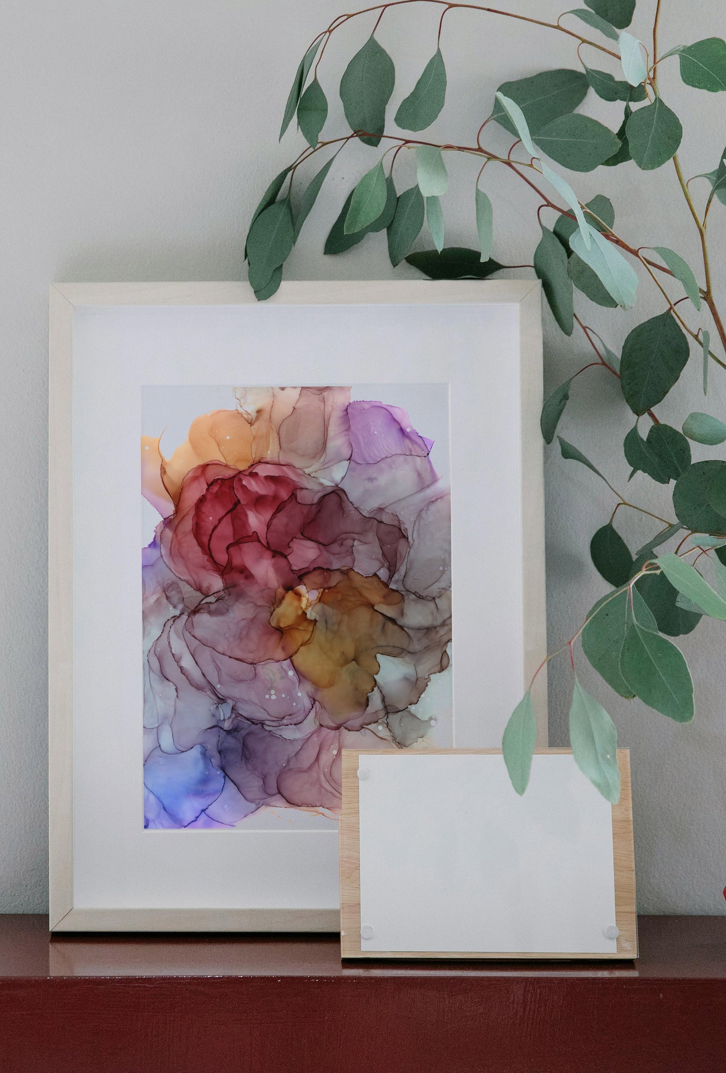 Zoomed out digital mockup of Beautiful thoughts framed in light wood sitting on a wooden table against a white wall. A vase with greenery sits off to the side.