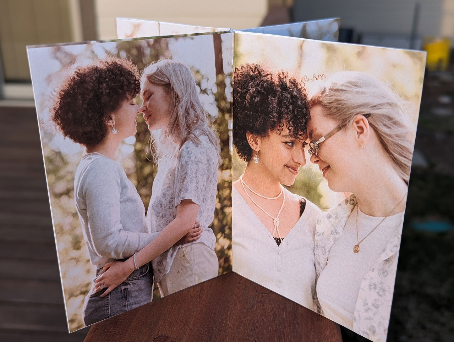 Centerpiece sitting on a wooden railing showing pictures of an LGBTQ+ couple facing each other about to kiss and a photo of them smiling and touching foreheads.