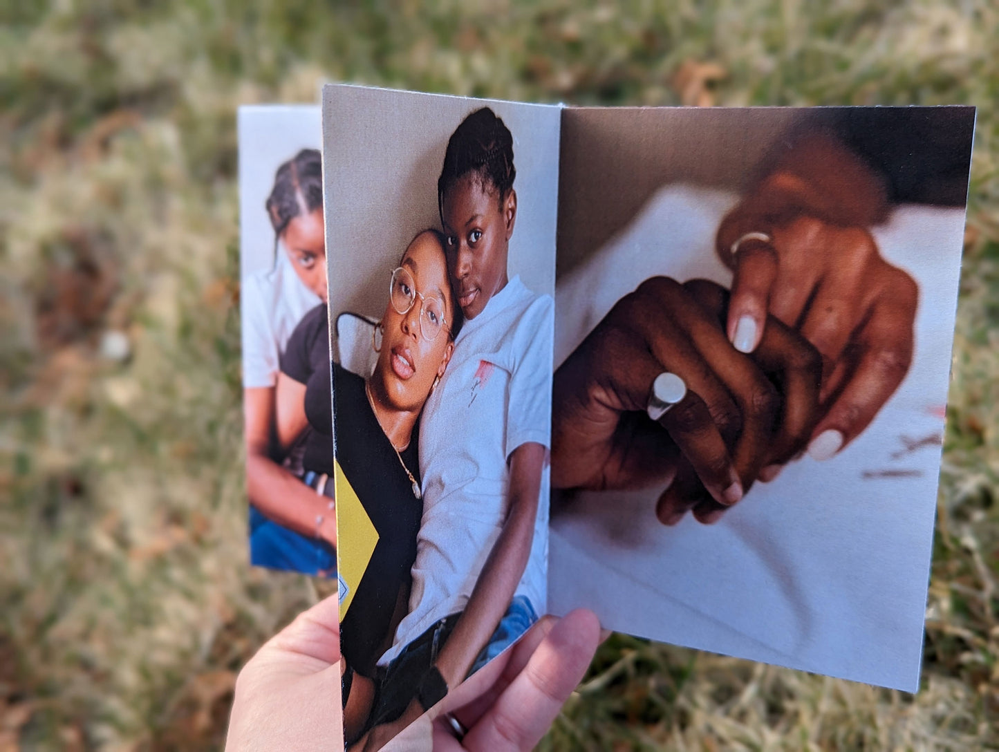 A hand holds a centerpiece showing an LGBTQ+ couple leaning against one another and their hands showing off their rings.