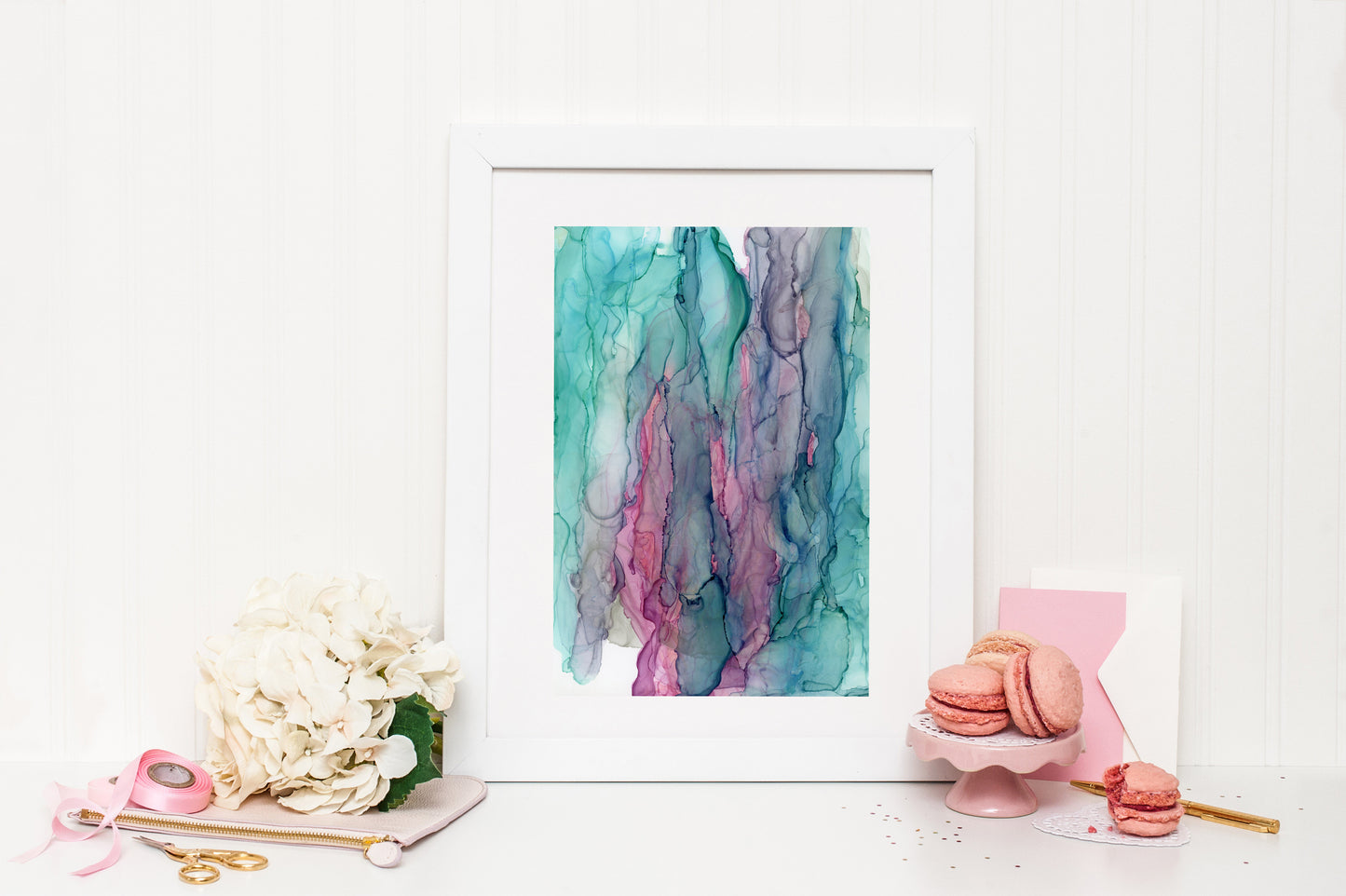Digital mockup of Connecting to the Magic framed in white surrounded by pink and white accessories: macroons, flower bloom, ribbon, scissors, and stationery.