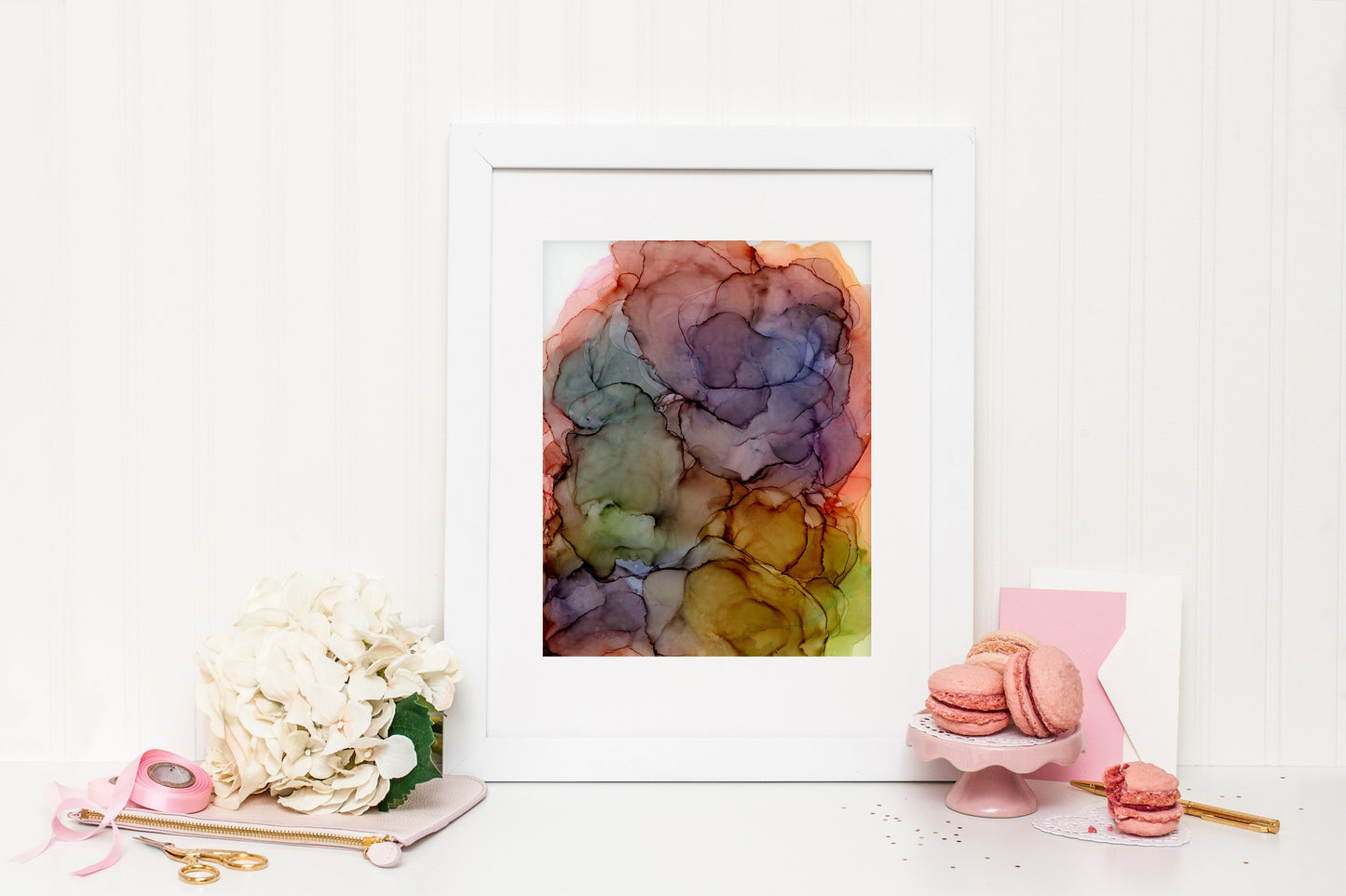 Digital mockup of Endless Possibilities framed in white surrounded by pink and white accessories: macroons, flower bloom, ribbon, scissors, and stationery.