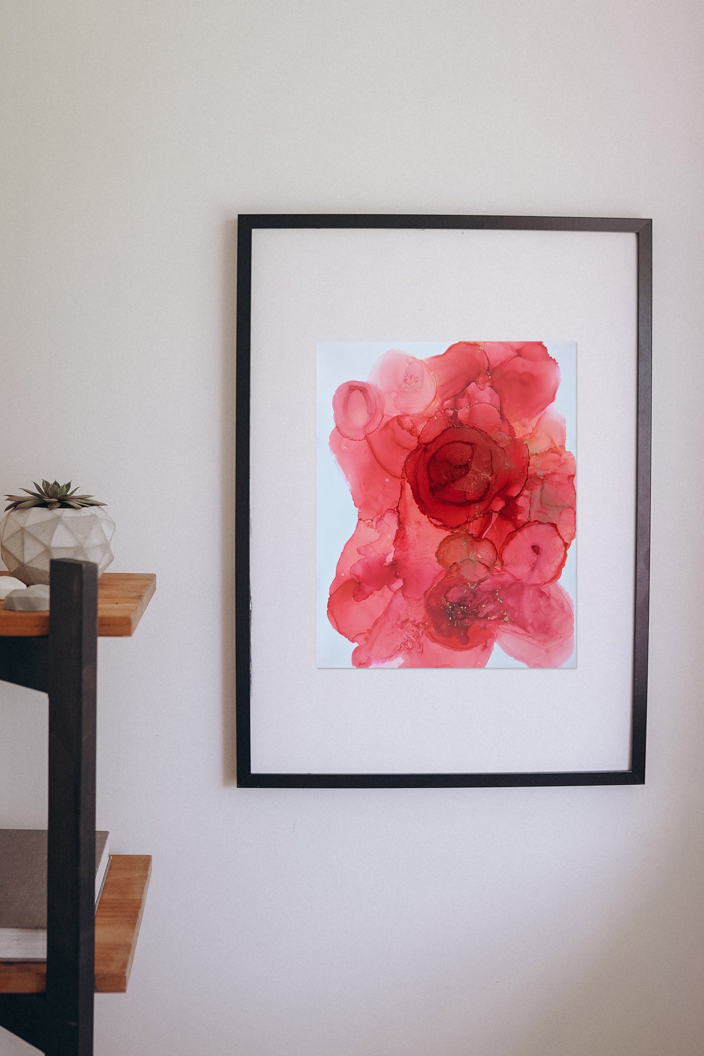 Digital mockup of Extraordinary Energy framed in black hung on a white wall with a wooden shelf off to the side.