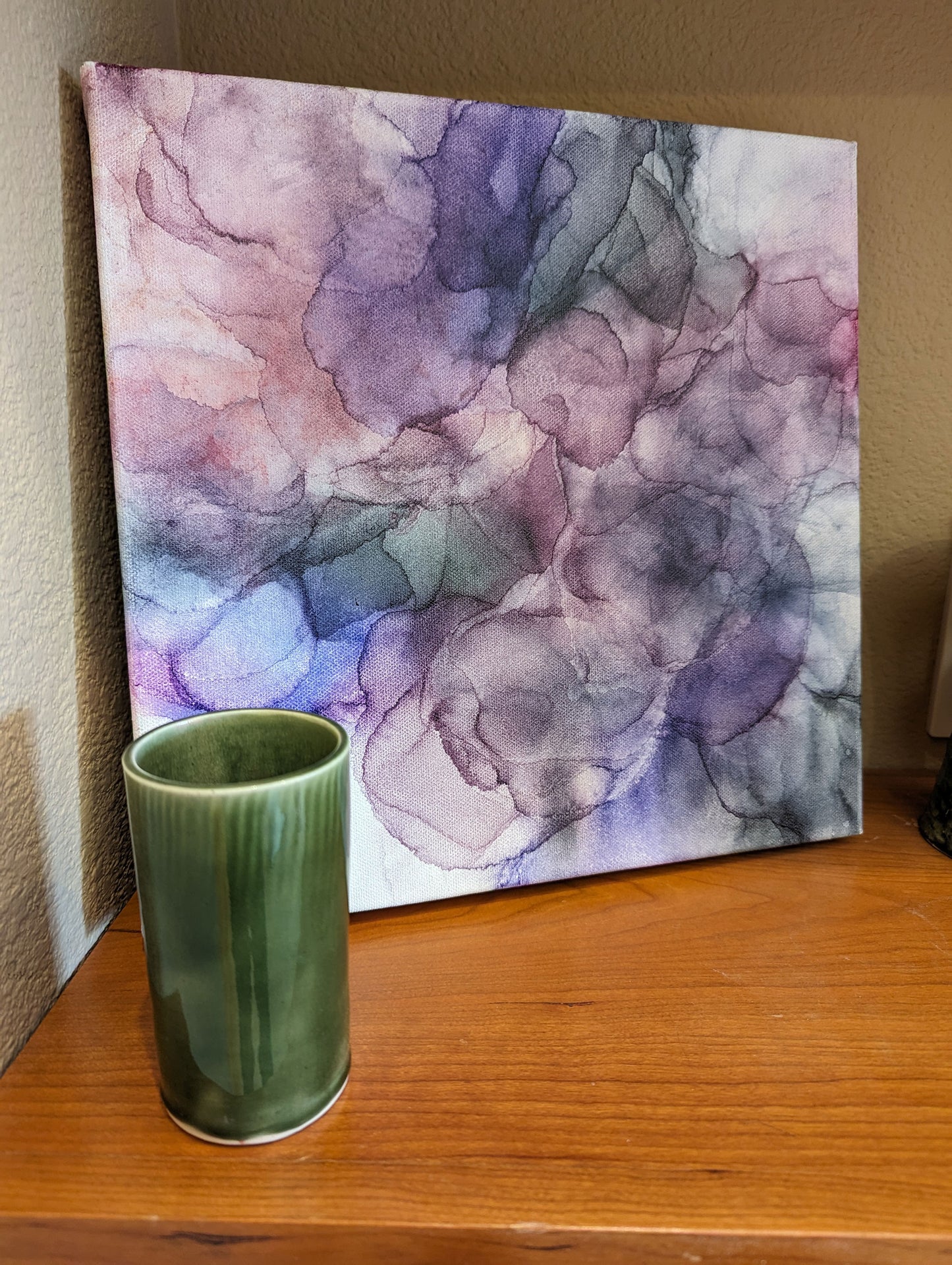 Canvas leaning on a wooden shelf with ceramic vases next to it.