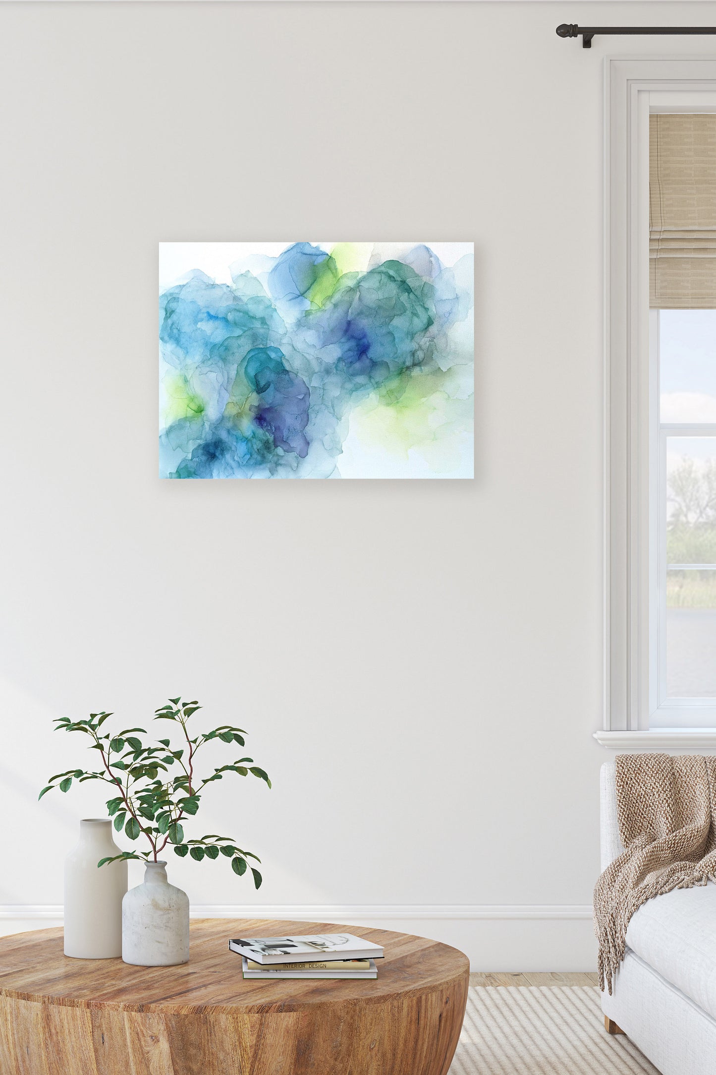 Digital mockup of Celebrated Changes hung on a white wall in a living room. A wooden coffee table with ceramic vases, greens, and a stack of books is in the foreground.