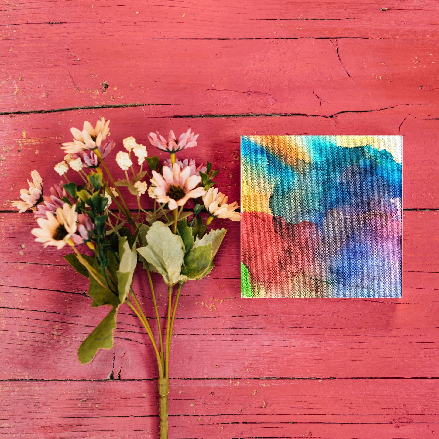 Digital mockup of the canvas laying on red painted boards next to stems of flowers.