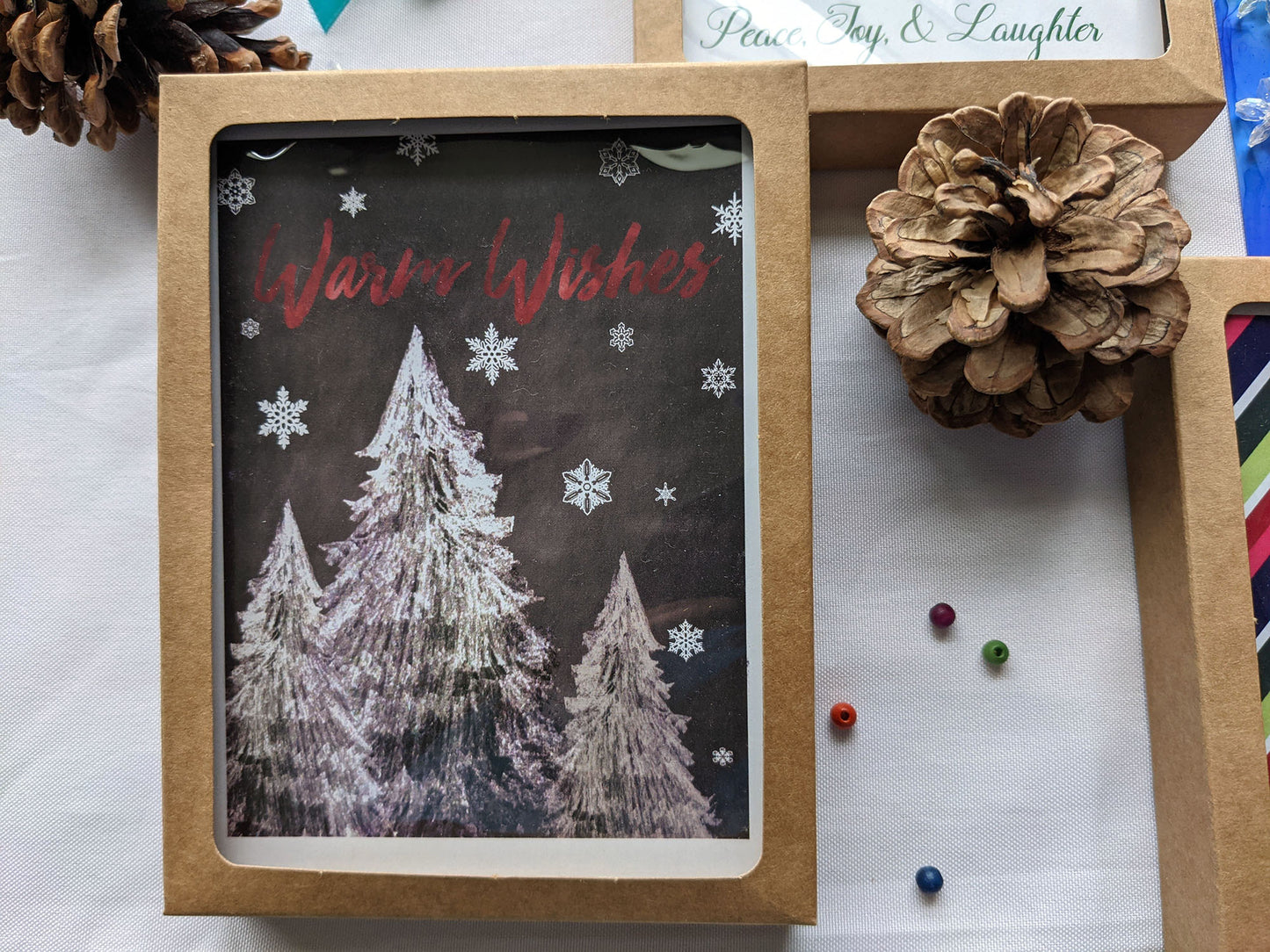 Kraft boxes of greeting cards on a white background with pinecones.