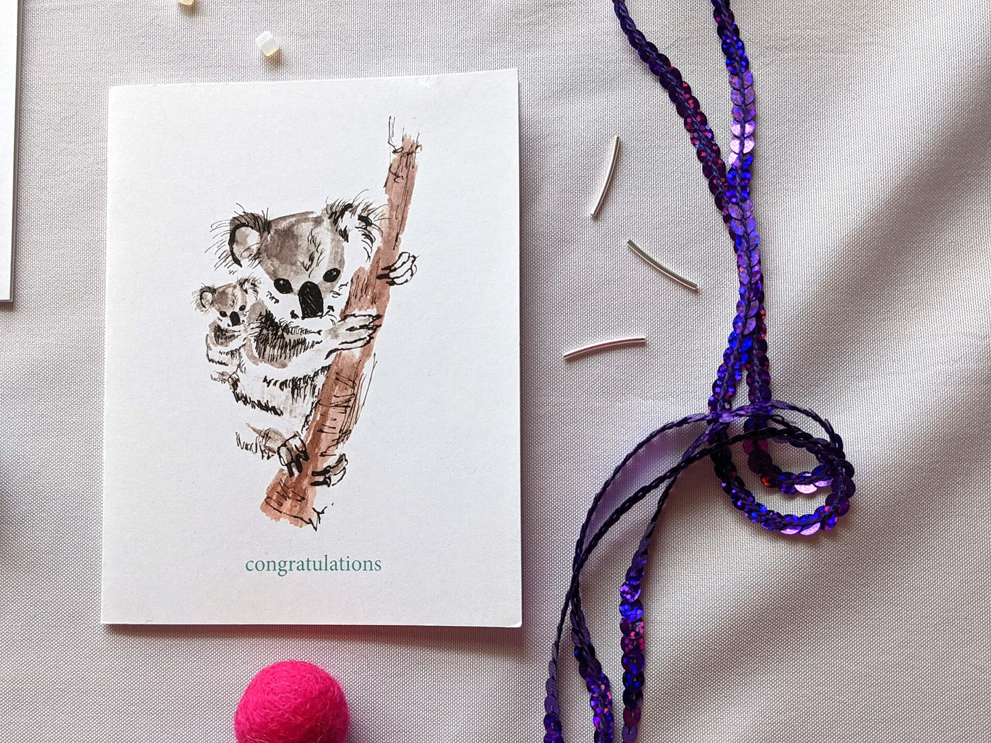 Greeting card laying on a white background with colorful felt balls, beads, and sequins.