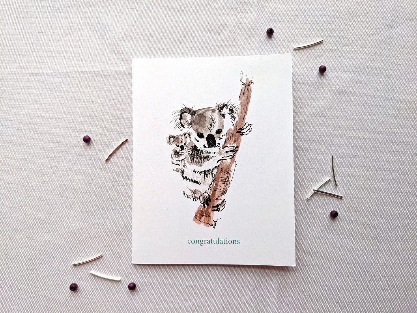 Greeting card on a white background with metallic and wooden beads.