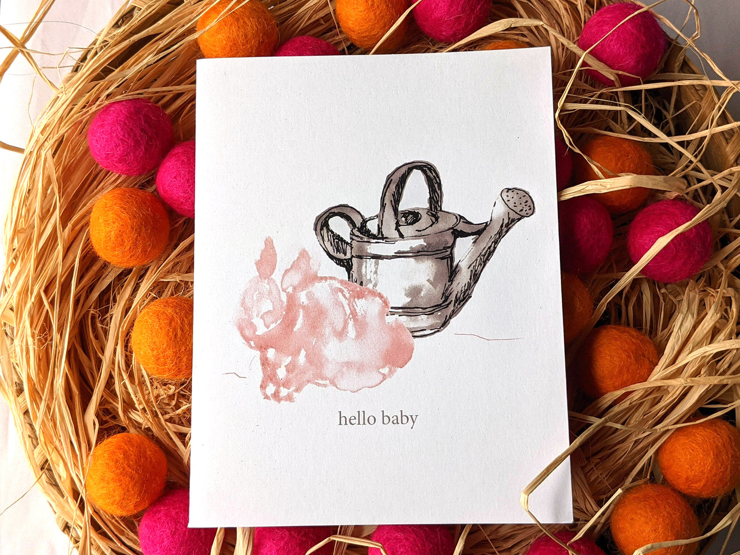 Greeting card on a woven basket filled with raffia and colorful felt balls.