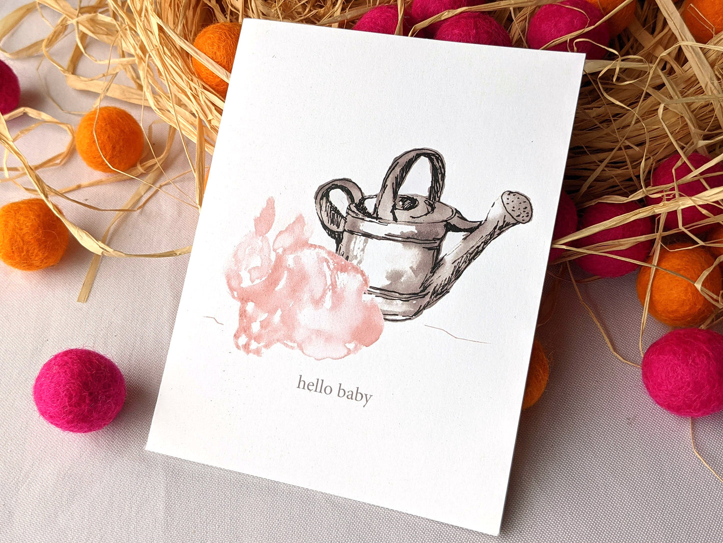 Greeting card leaning on a pile of raffia and colorful felt balls.