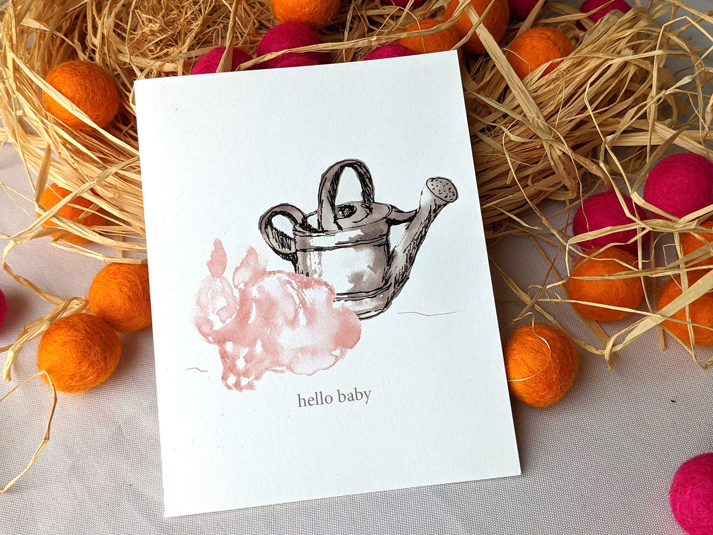 Greeting card leaning on a pile of raffia and colorful felt balls.