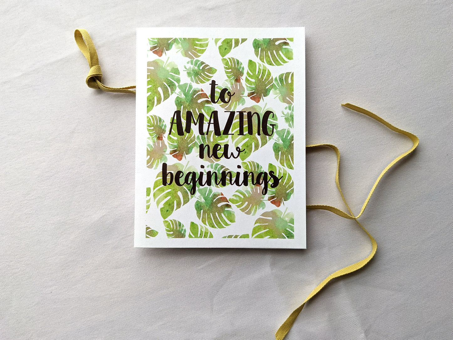 Greeting card laying with colorful envelope on white background with a colorful cotton ribbon.