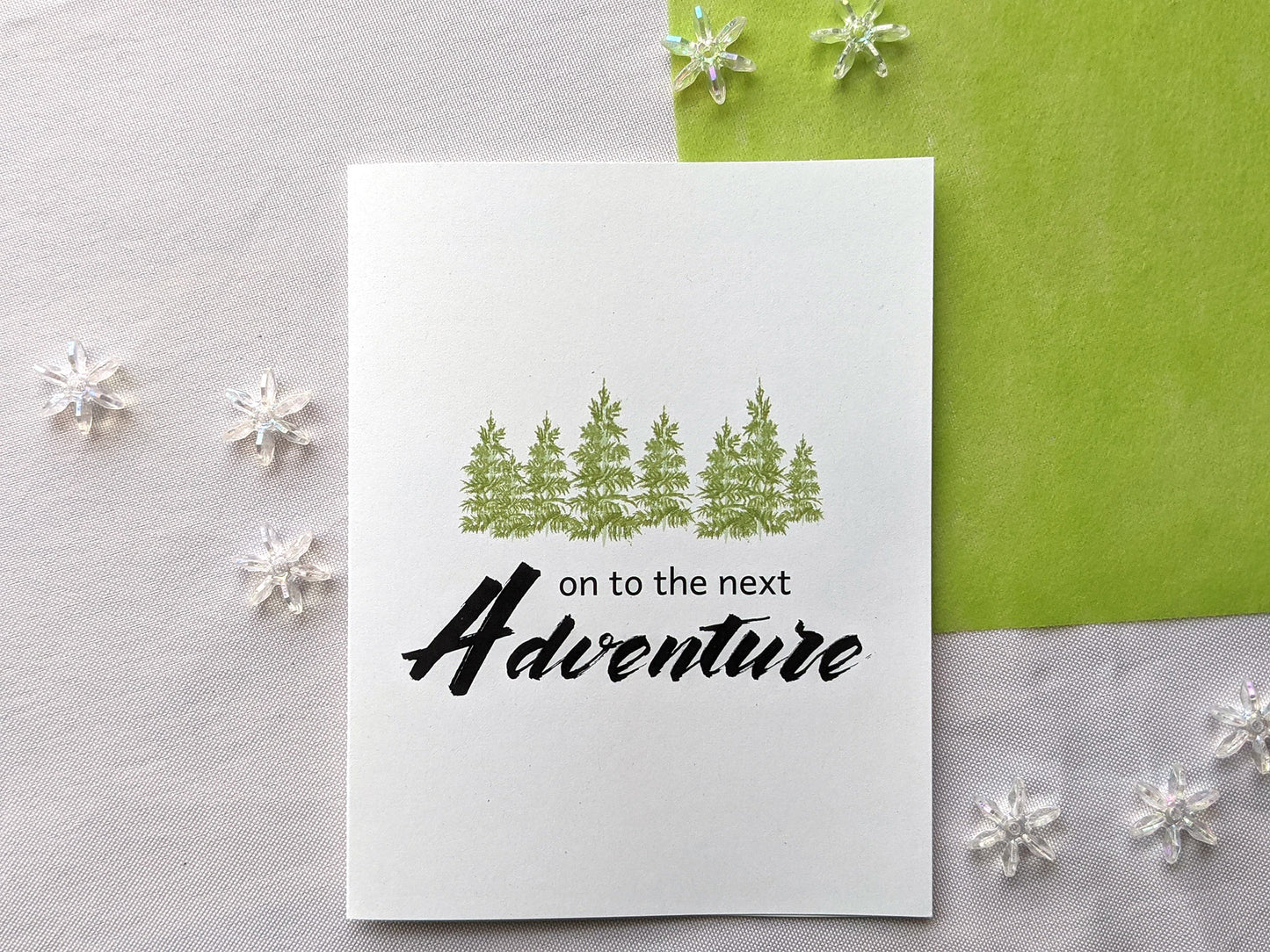 Greeting card on a white background with bright green tissue and snowflake shaped beads.