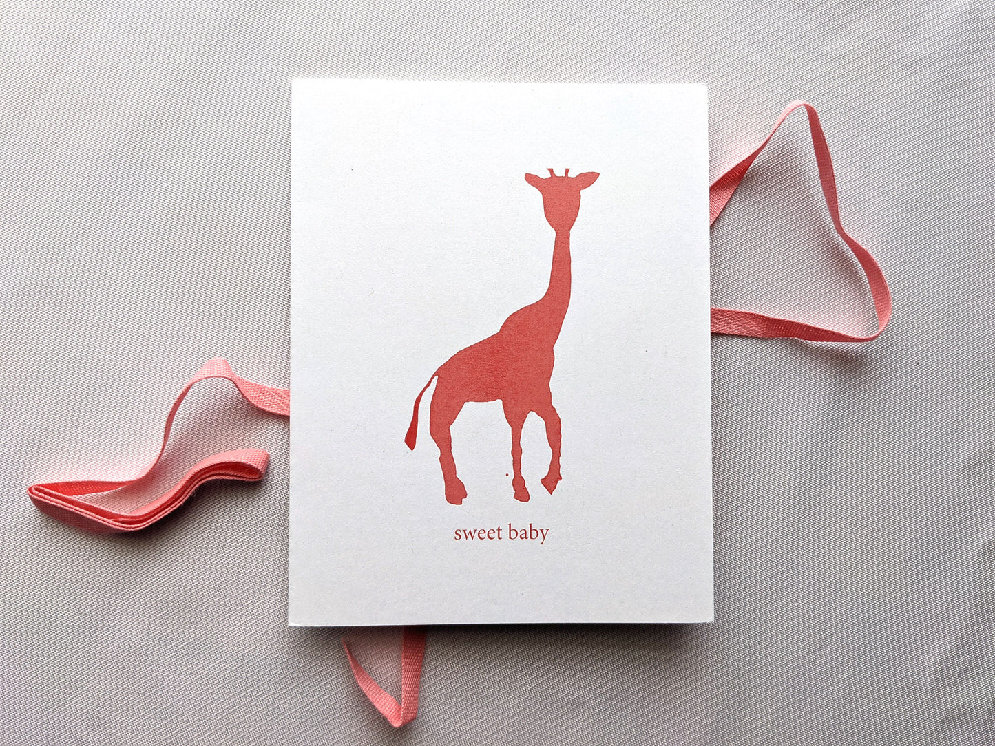 Greeting card laying on a white background with a pink cotton ribbon.