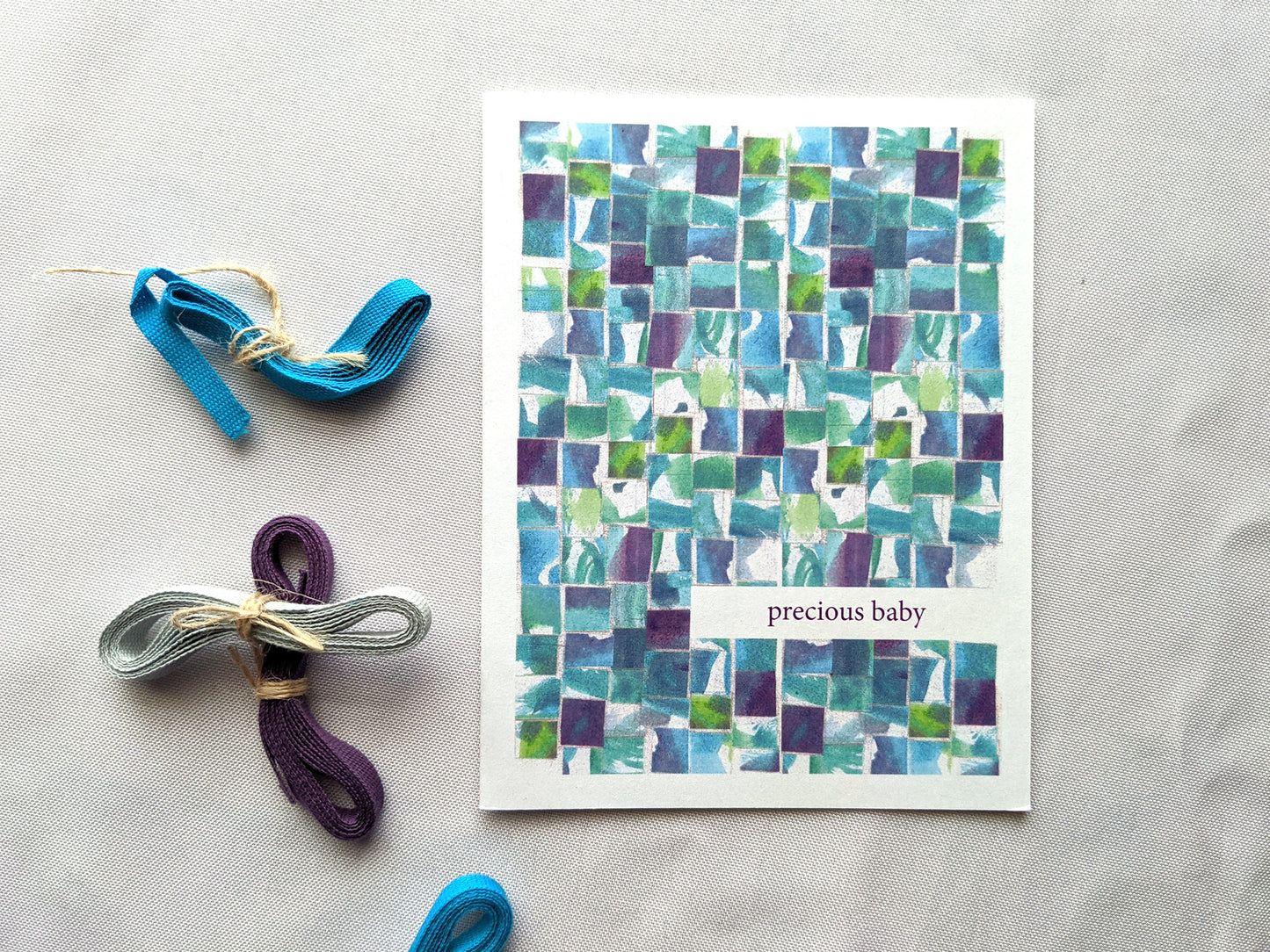 Greeting card laying on a white background with colorful cotton ribbon.