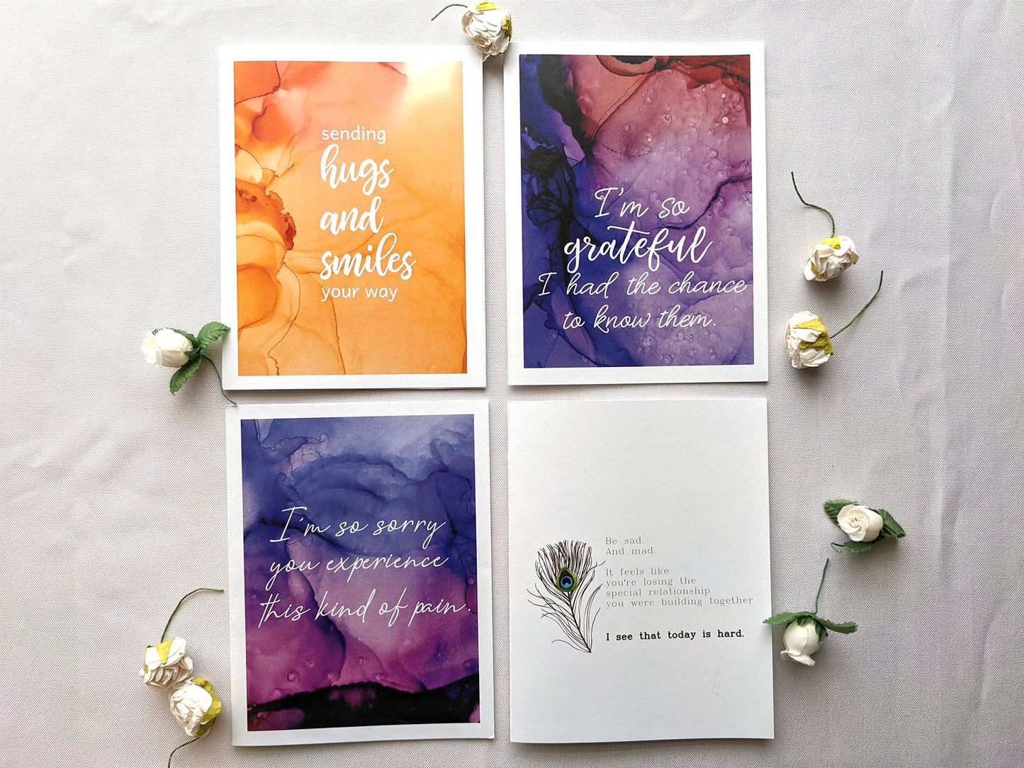 Four greeting cards laying on a white background with faux flower buds.