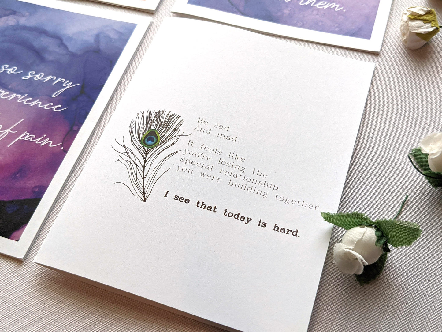 Angled view of greeting cards laying on a white background with faux flower buds.